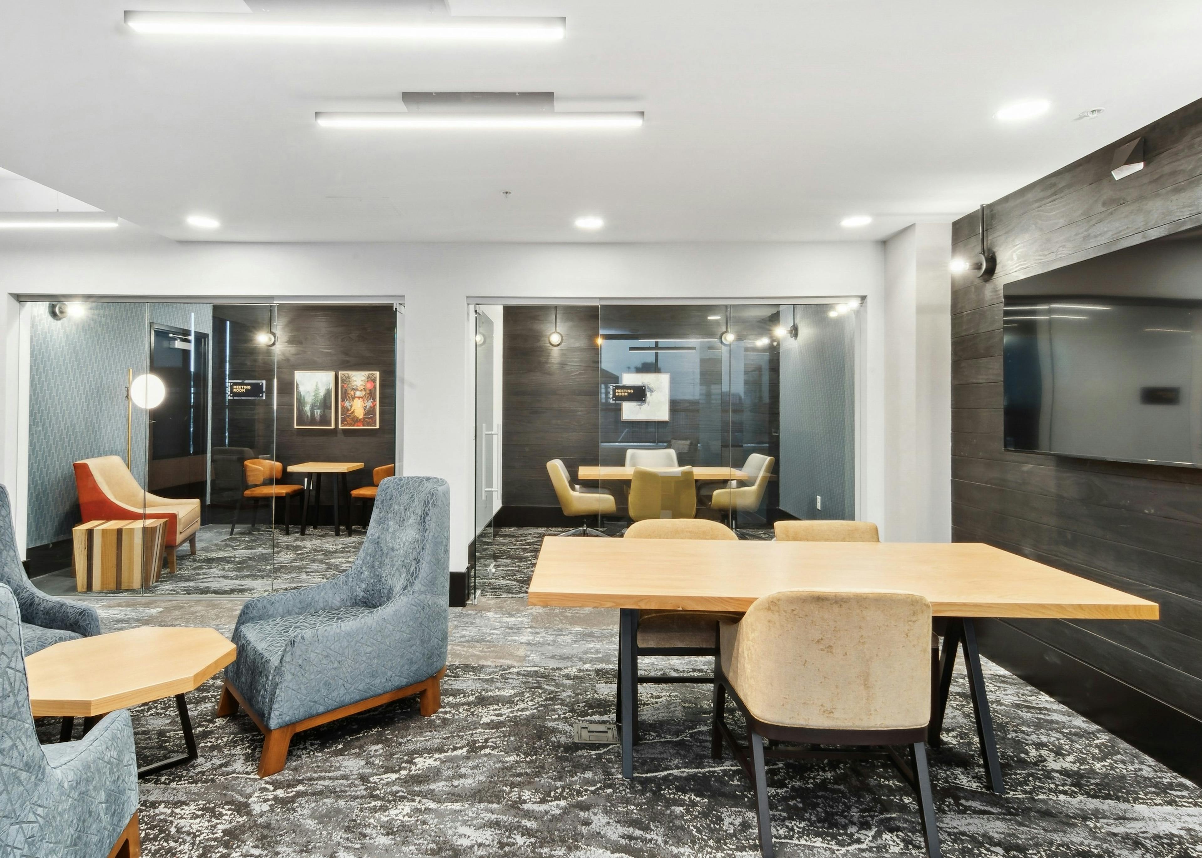 Interior view of a business center at AMLI RiNo with conference tables and plush chairs and 2 glass wall meeting rooms