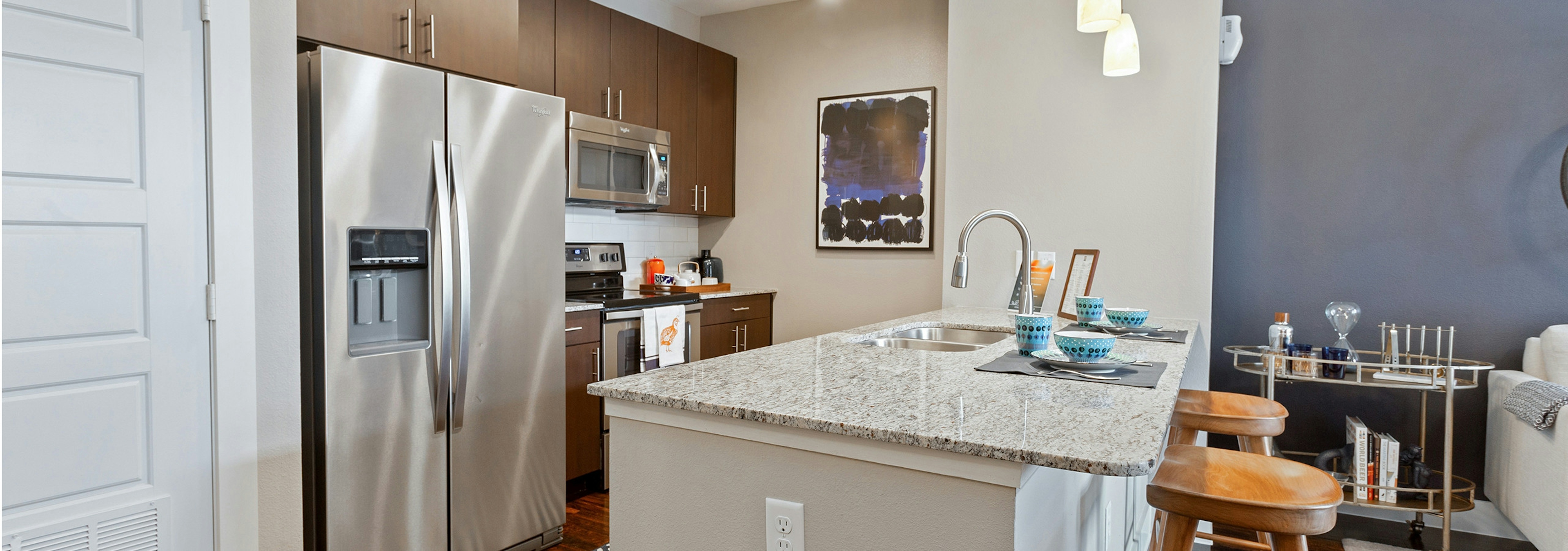 AMLI Covered Bridge model kitchen with Whirlpool stainless steel appliances, granite countertops, and a French door refrigerator