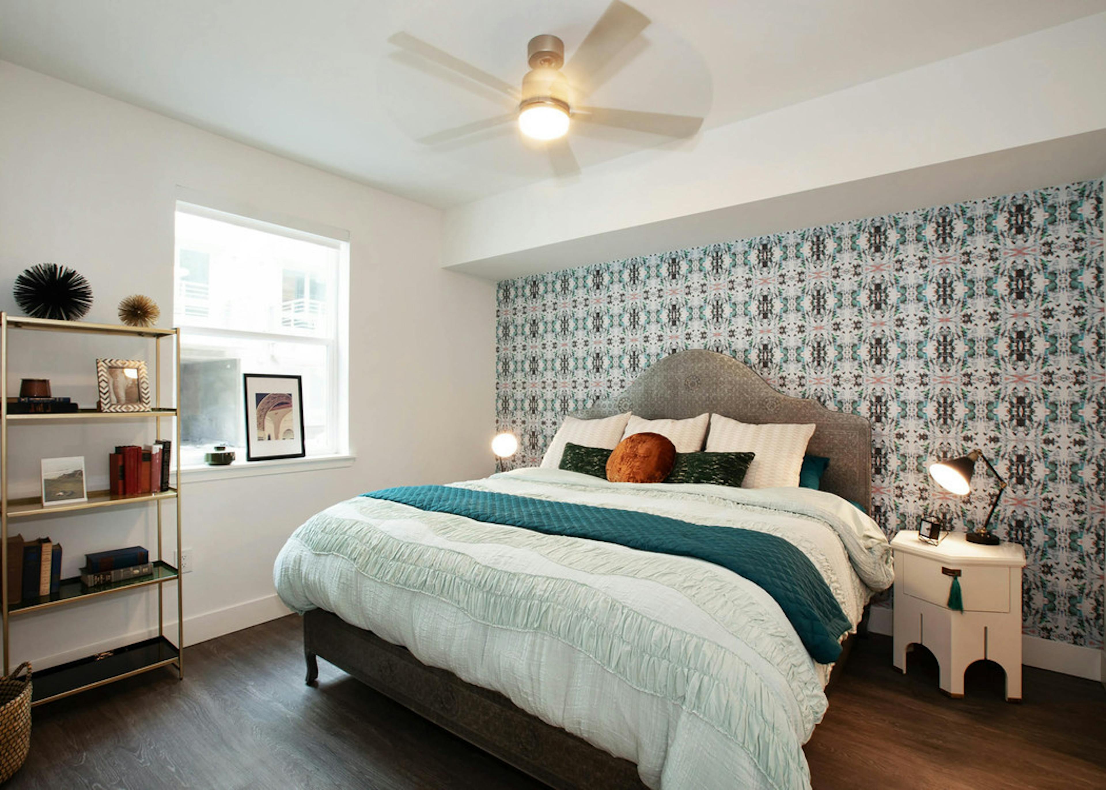 Interior of AMLI Park Broadway apartment bedroom with patterned wall paper behind a king size bed and night stand with lamp