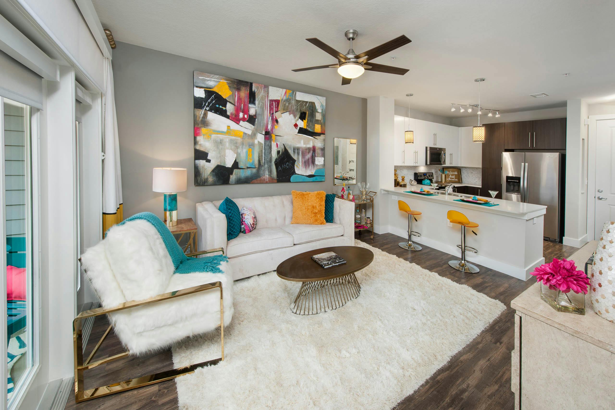 AMLI Piedmont Heights kitchen and living room showing white couches and grey walls with dark floor and counter with barstools