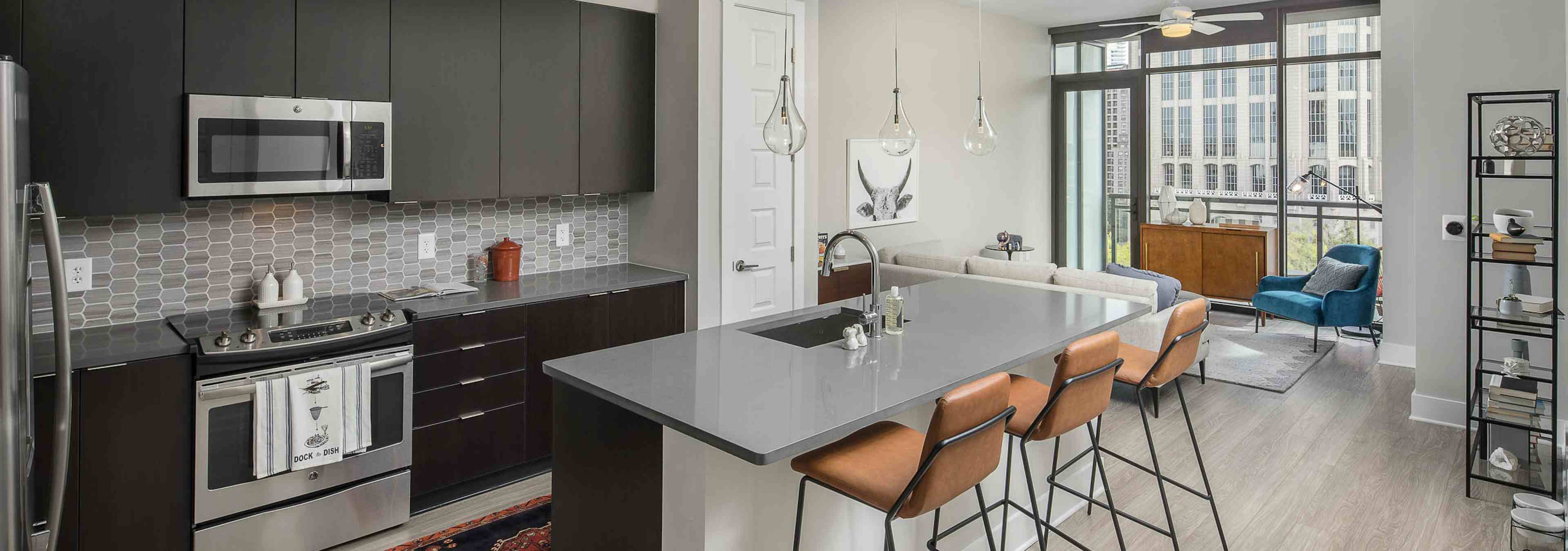 Kitchen at AMLI Arts Center with black cabinets and sleek grey countertops with a light grey patterned backsplash and island