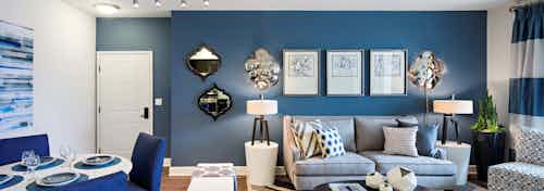Interior of AMLI Spanish HIlls apartment living room with blue accent wall and peek into dining area with fully set table