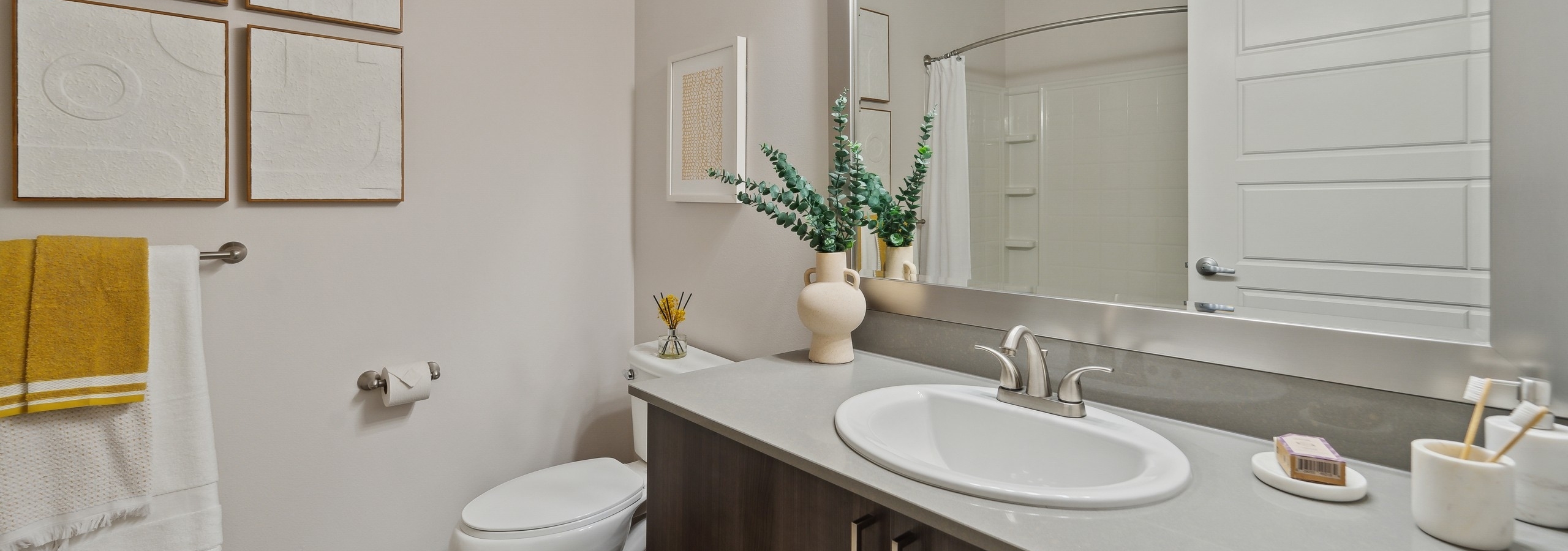 AMLI South Lake Union bathroom featuring a large mirror above a long vanity with single white sink and brushed nickel faucet