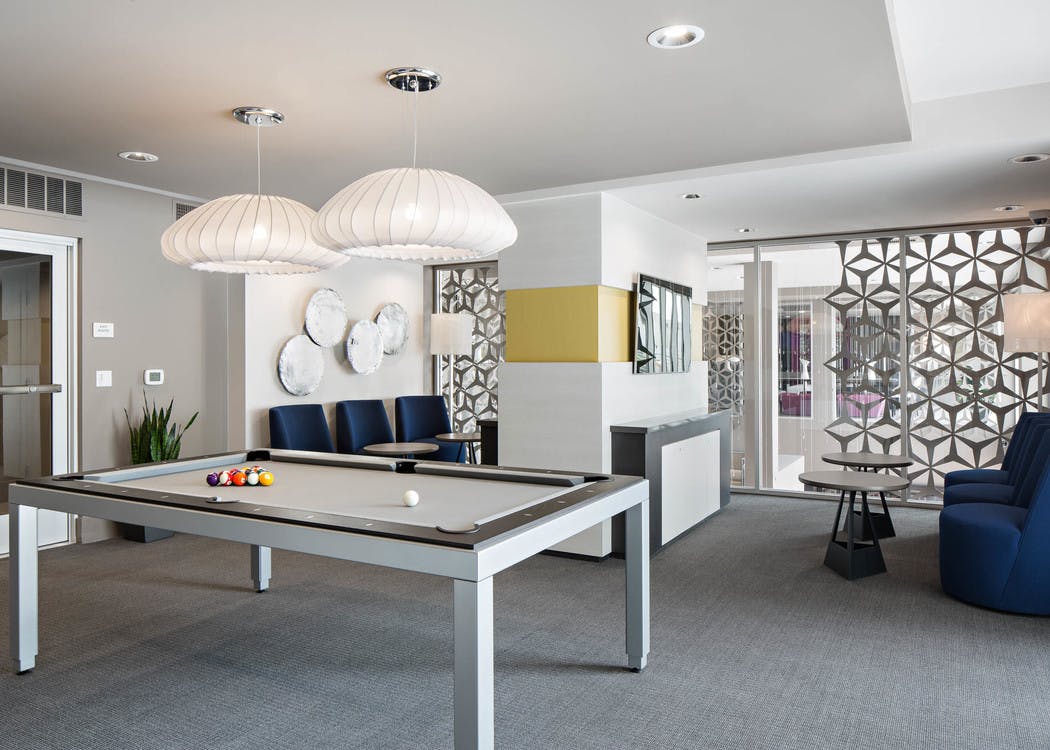 Interior view of gaming lounge at AMLI Lex on Orange apartments with white coral-shaped lighting above pool table and seating
