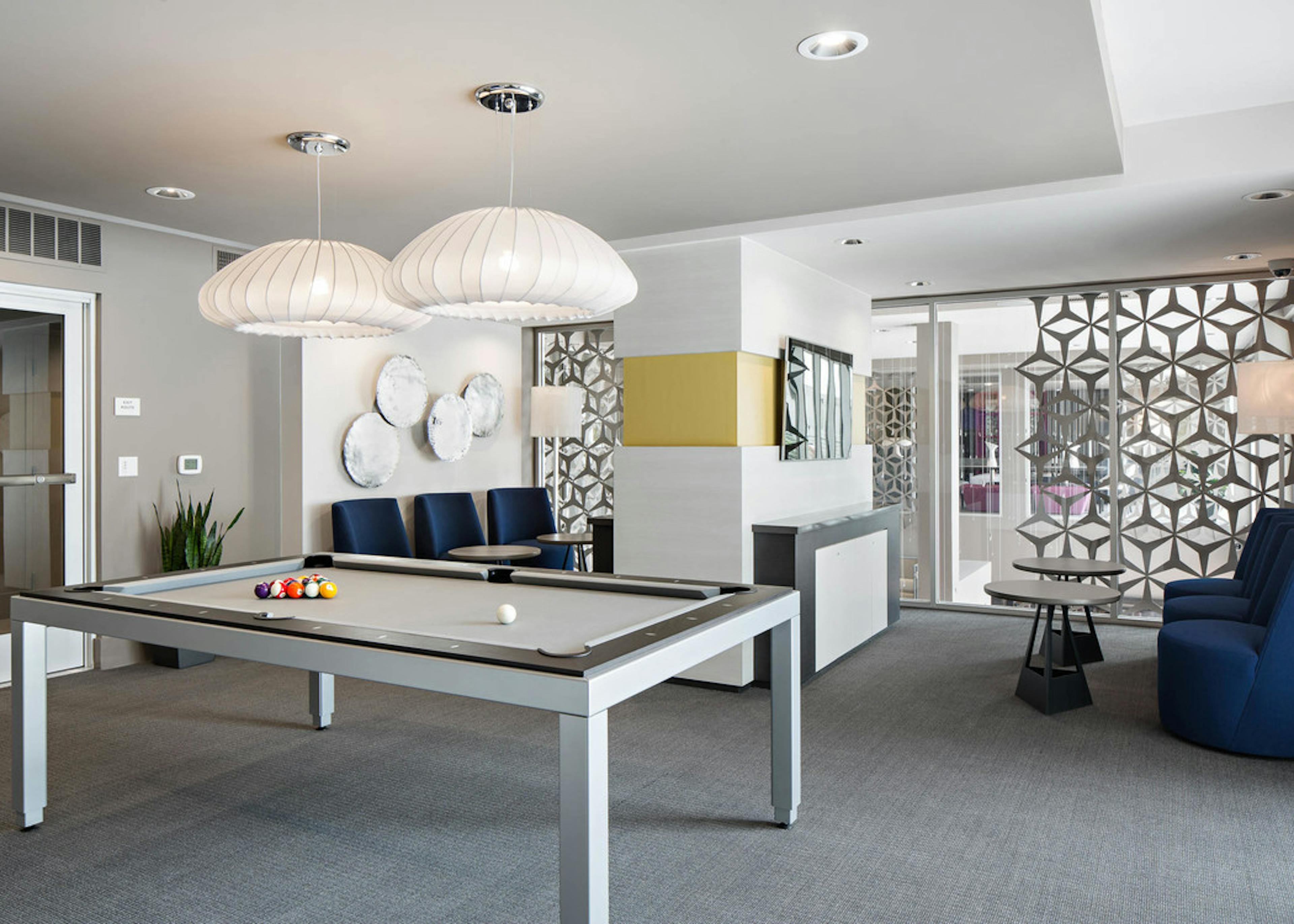 Interior view of gaming lounge at AMLI Lex on Orange apartments with white coral-shaped lighting above pool table and seating