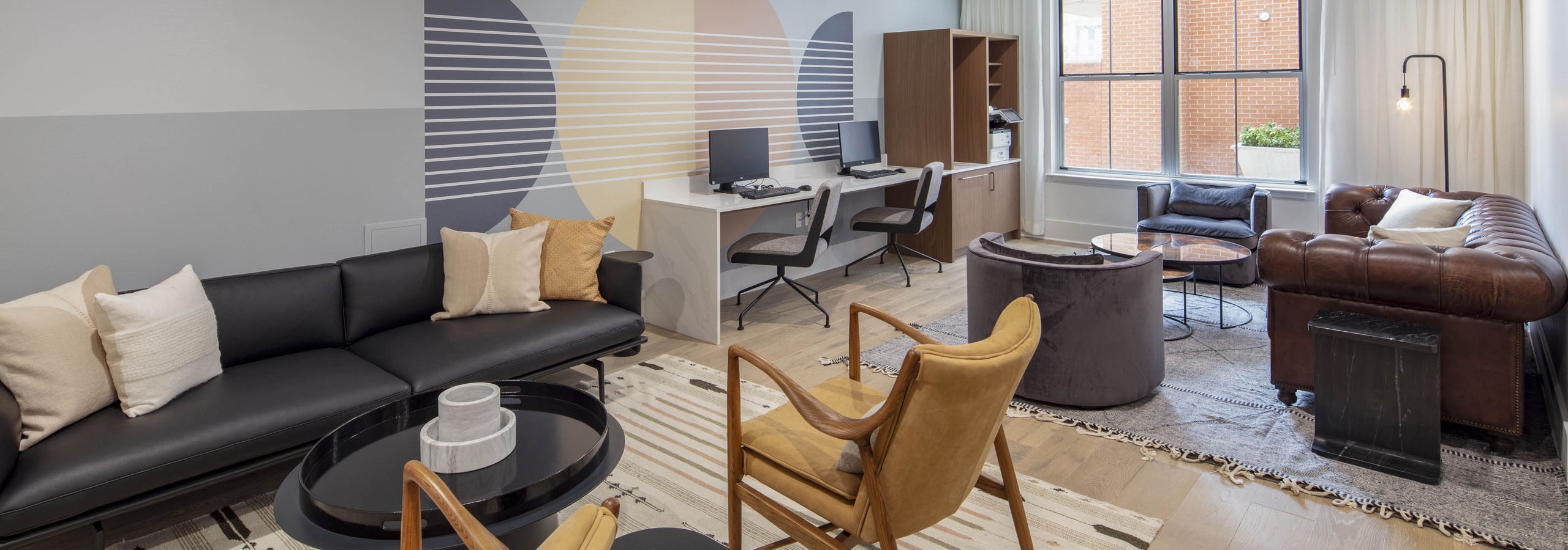 Business center at AMLI Downtown apartments with two computer stations and printer and 2 leather seating areas on area rugs