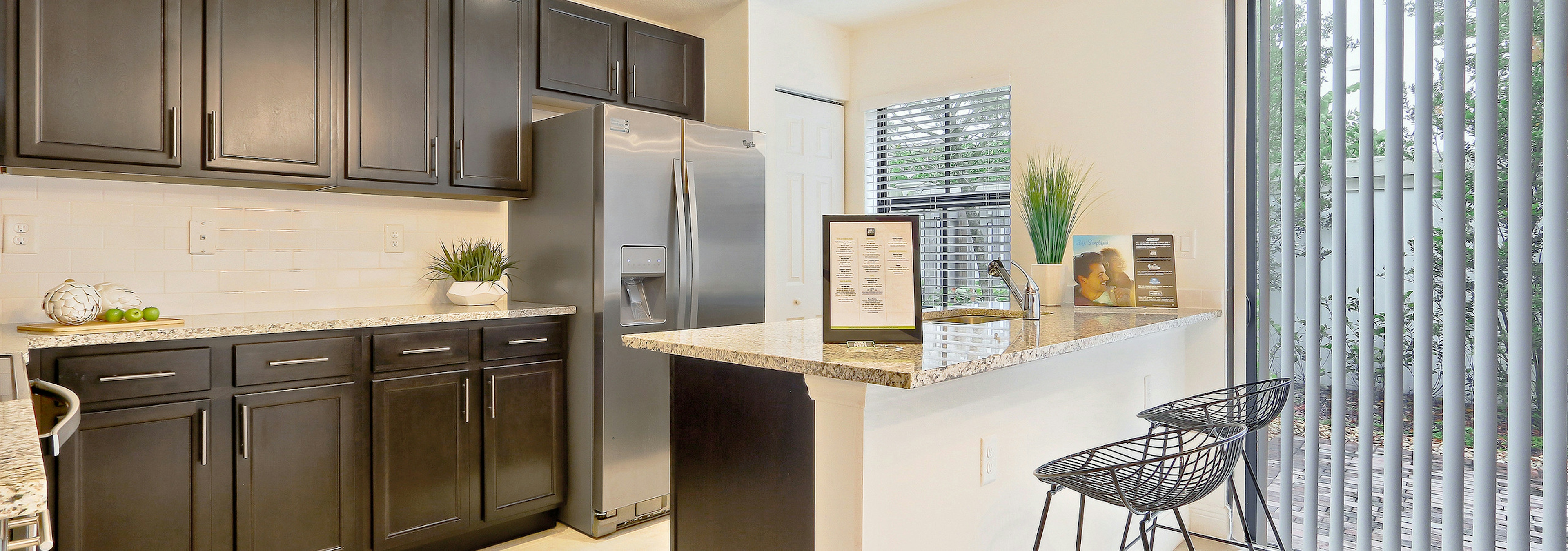 Interior view of AMLI Toscana Place townhome kitchen with counter, stools, stainless steel appliances and designer cabinets