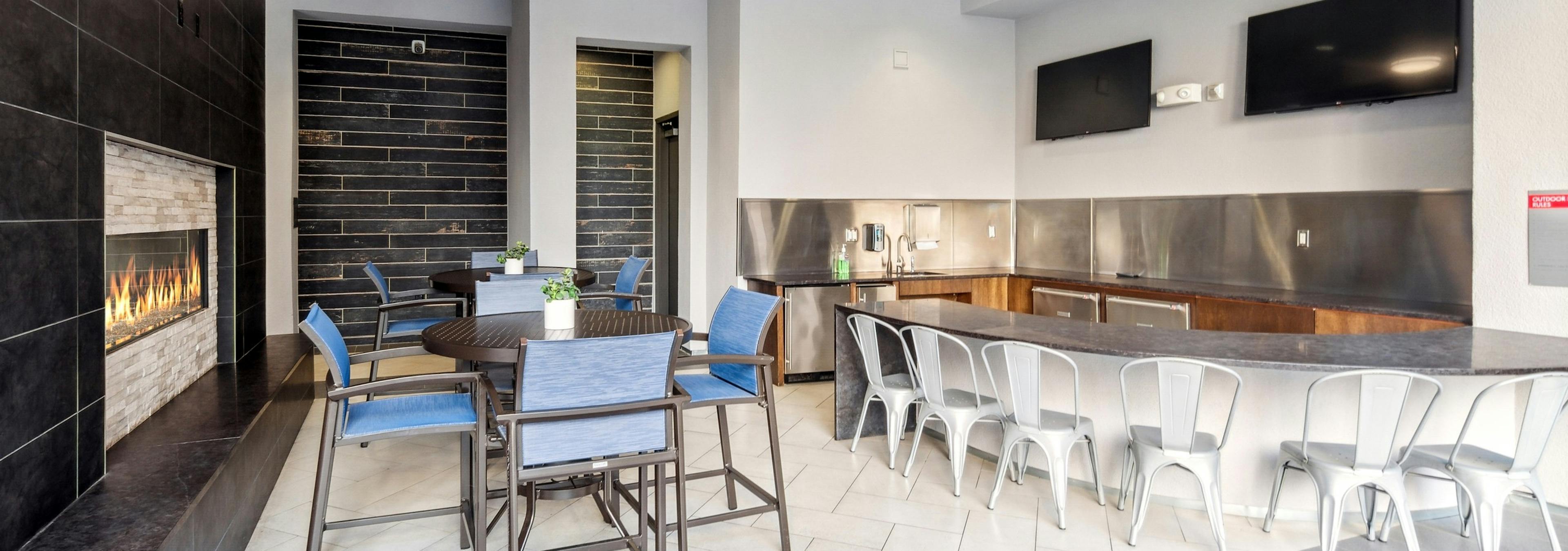AMLI Denargo Market outdoor living room with fireplace and tables and chairs and TVs and wet bar with many chairs