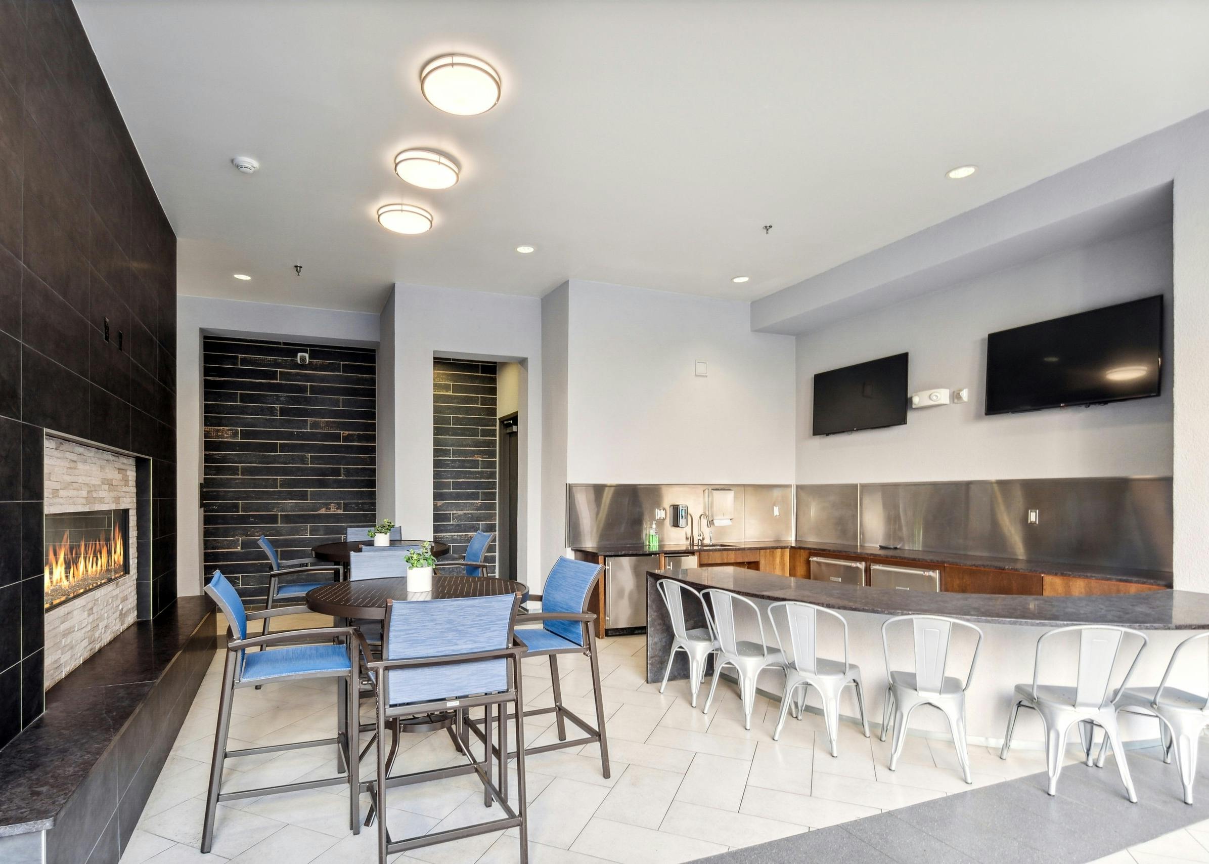 AMLI Denargo Market outdoor living room with fireplace and tables and chairs and TVs and wet bar with many chairs