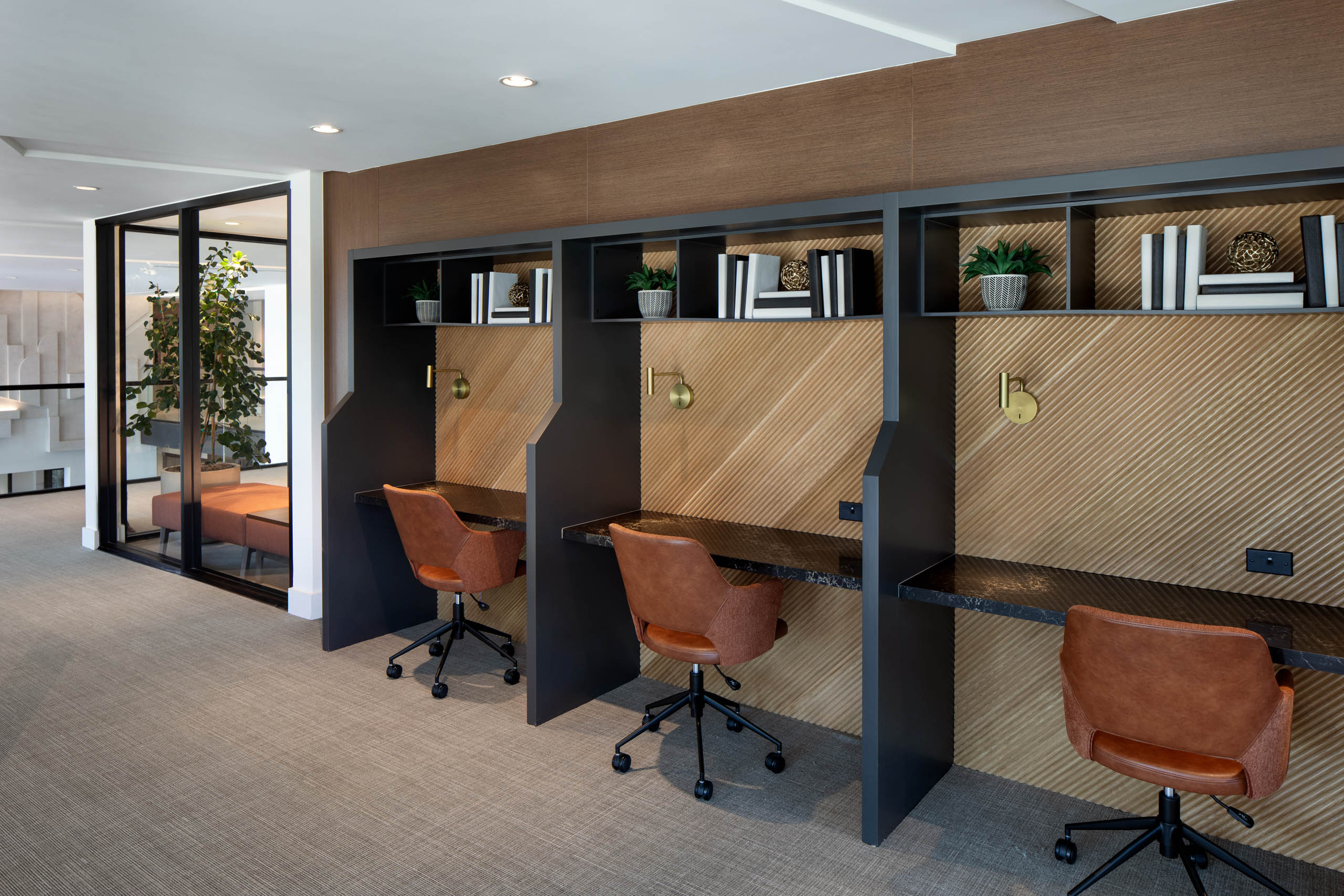 Shared workspace with private desk cubicles, rolling chairs, task lighting, wood accents, and glass-walled meeting rooms.