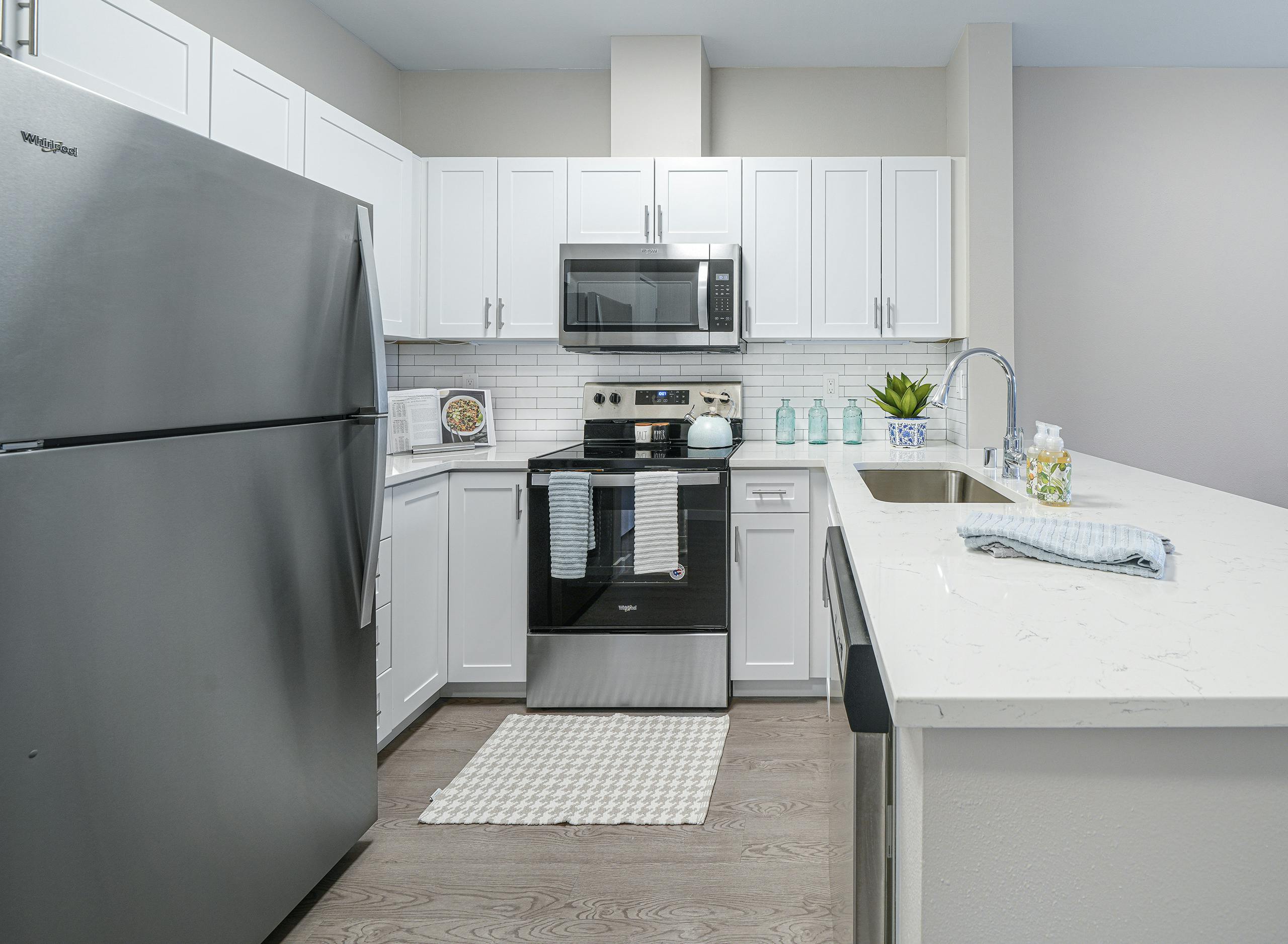 AMLI Bellevue Park apartment kitchen with stainless steel appliances and white cabinets and countertop and tiled backsplash