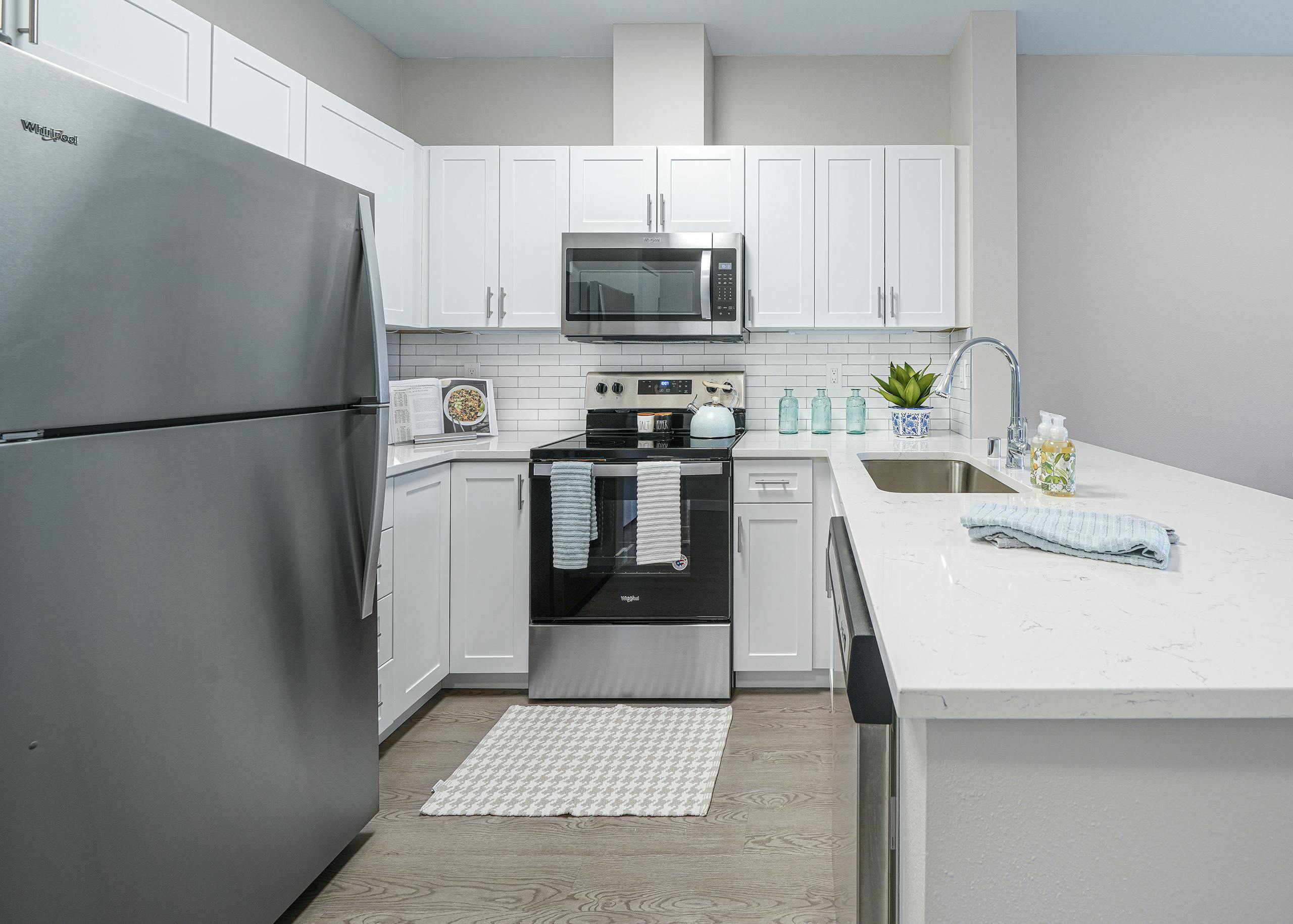 AMLI Bellevue Park apartment kitchen with stainless steel appliances and white cabinets and countertop and tiled backsplash