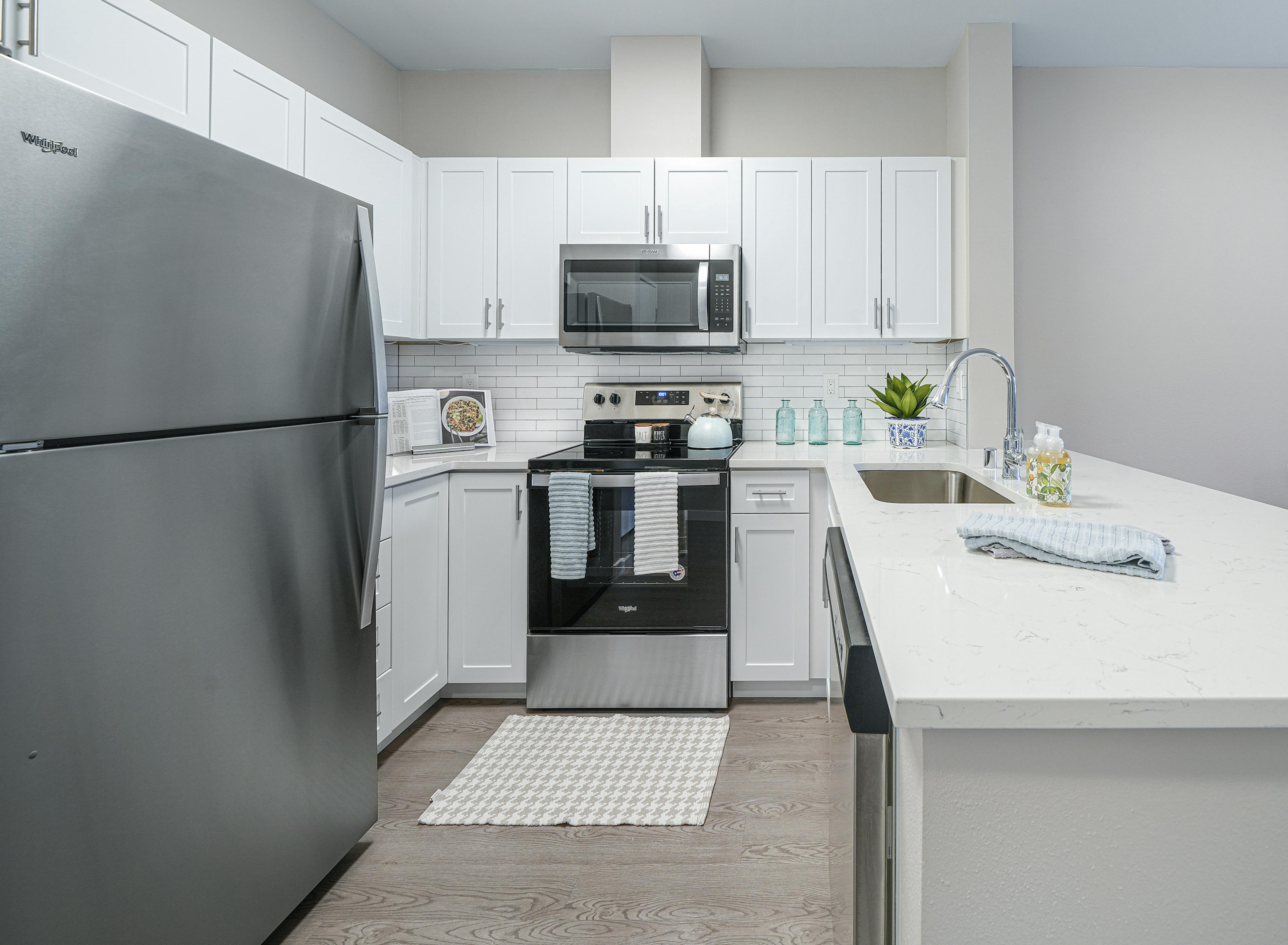 AMLI Bellevue Park apartment kitchen with stainless steel appliances and white cabinets and countertop and tiled backsplash