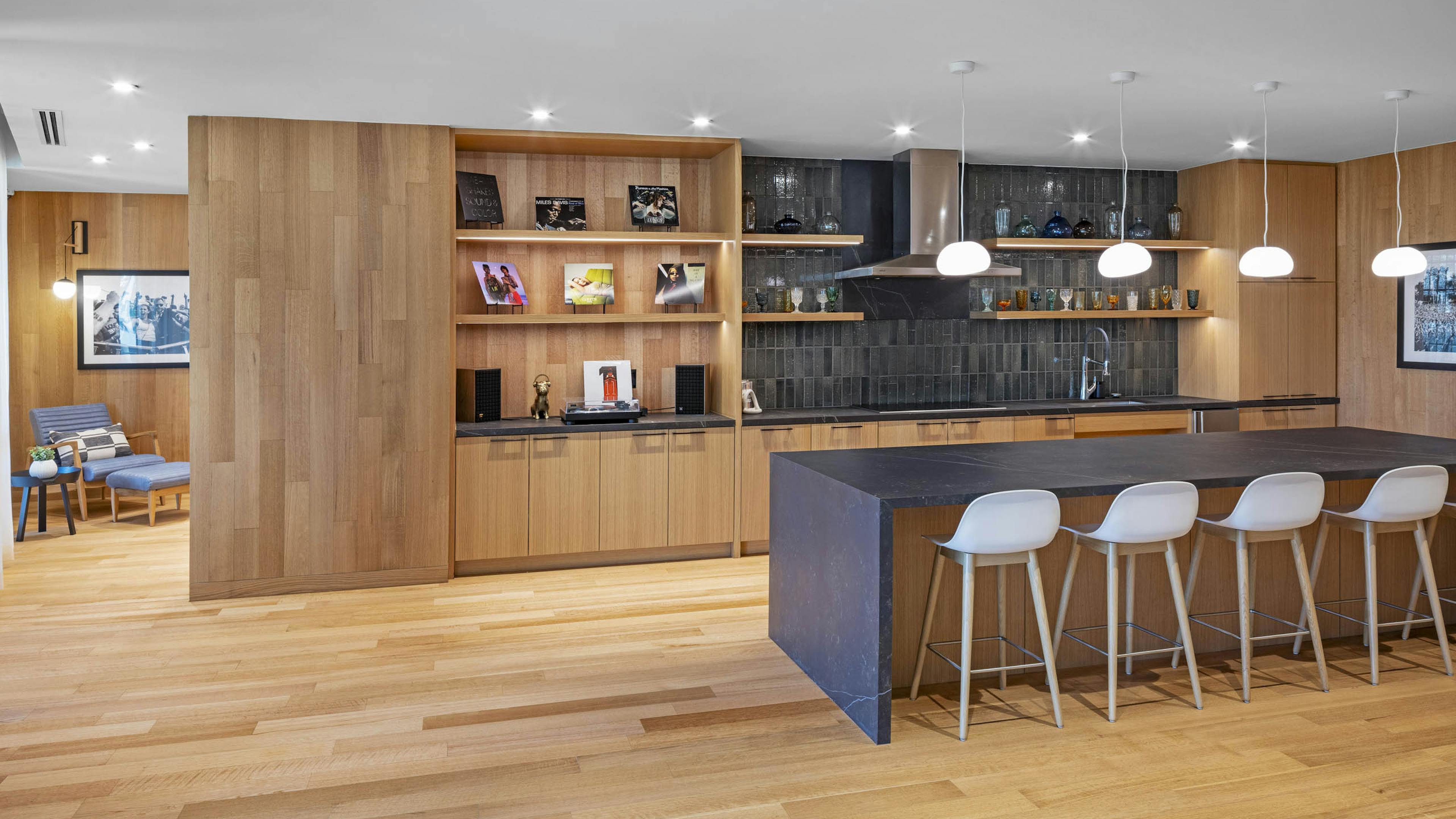 AMLI Branch Park apartments lounge with wood floors and walls and island serving kitchen with open shelves and grey tile wall
