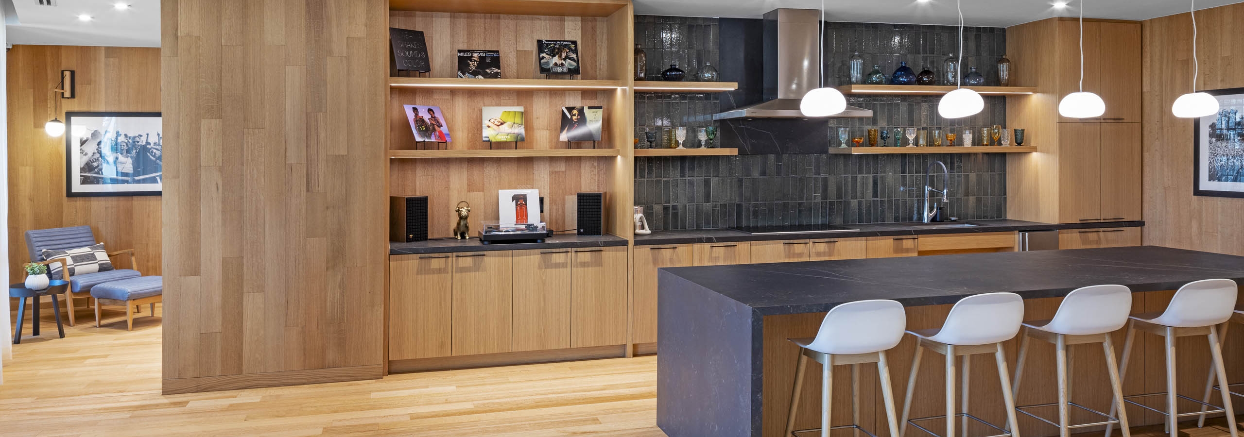 AMLI Branch Park apartments lounge with wood floors and walls and island serving kitchen with open shelves and grey tile wall