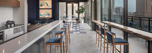 Skydeck at AMLI Arts Center with thin long counters across from each other with blue cushioned barstools facing windows