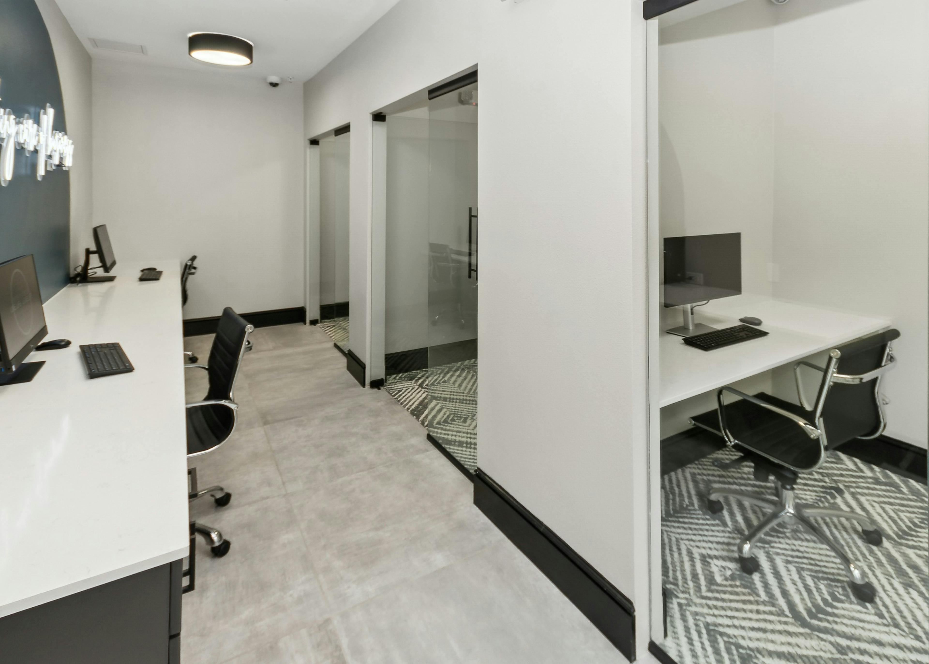AMLI Campion Trail business center with 2 computers on long white desk and private offices with computers and glass doors