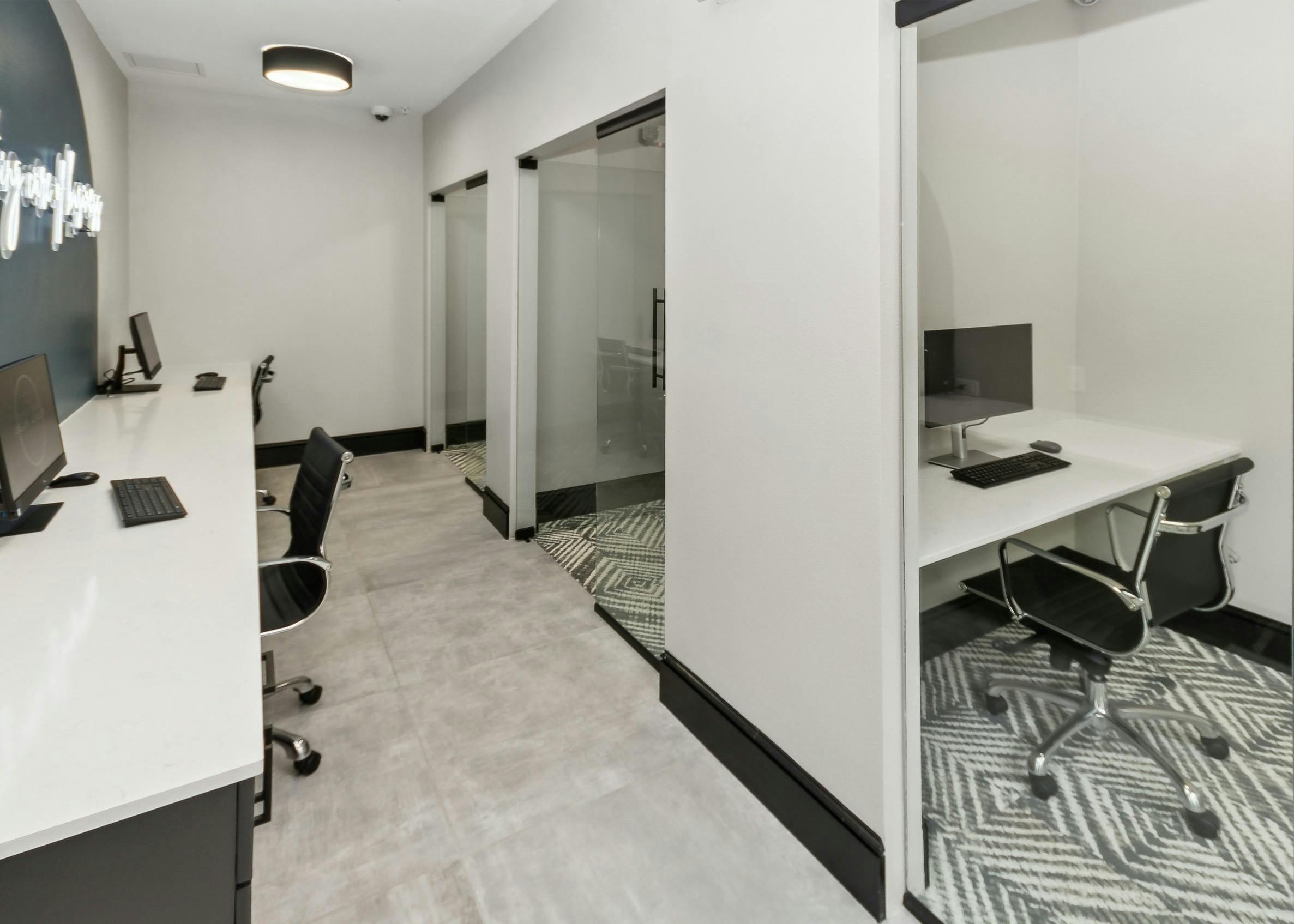AMLI Campion Trail business center with 2 computers on long white desk and private offices with computers and glass doors
