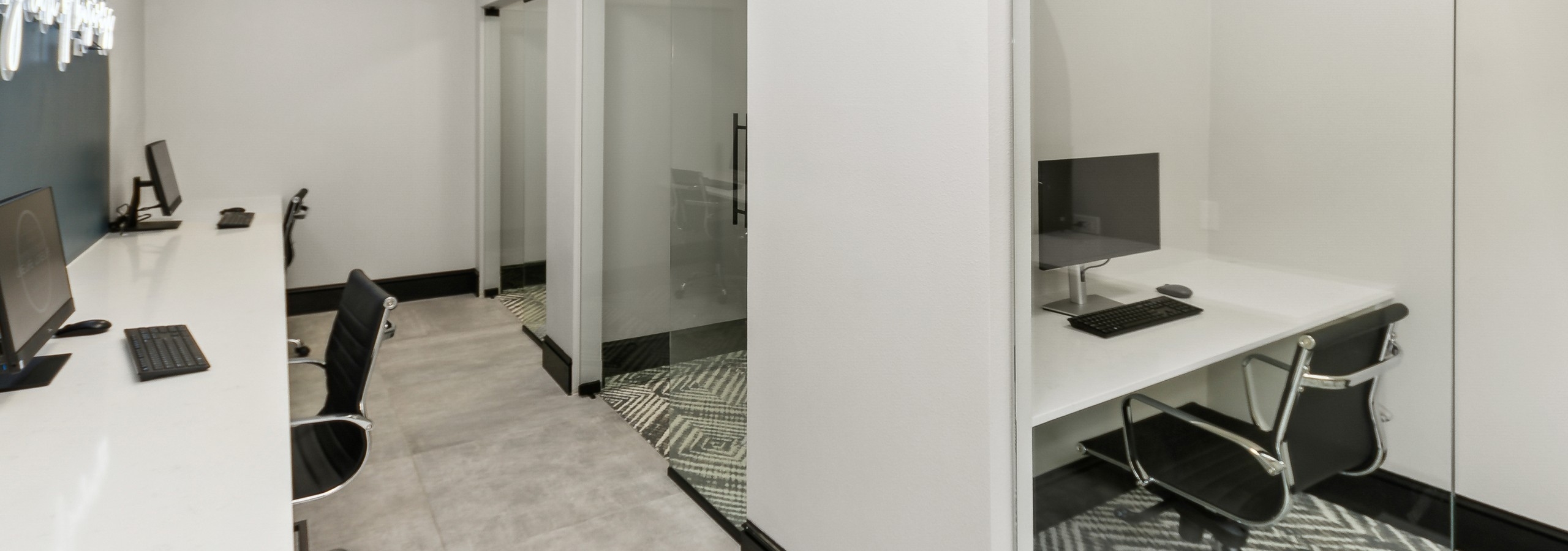 AMLI Campion Trail business center with 2 computers on long white desk and private offices with computers and glass doors