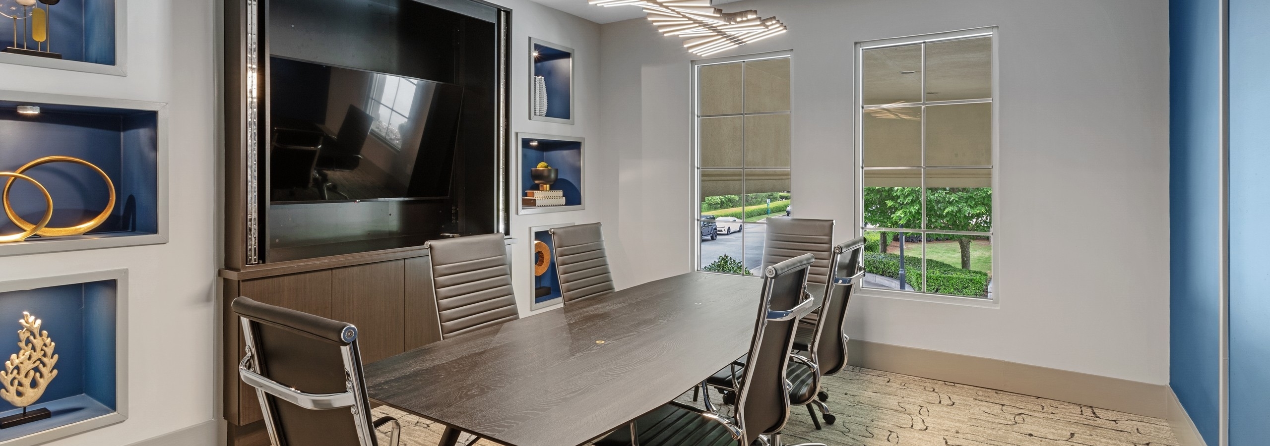 Conference room at AMLI North Point apartments with dark wood conference table and chairs with built in TV and side window