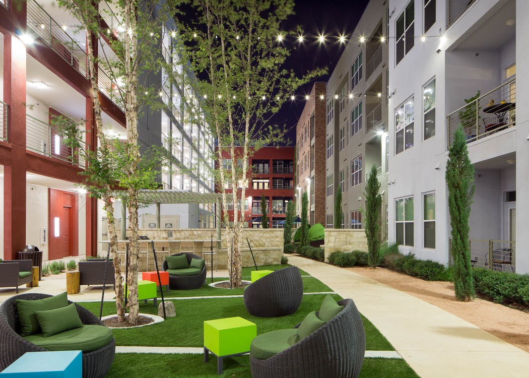 Courtyard at AMLI at Mueller with seating area on a grassy square in the center of surrounding pavement and shrubbery