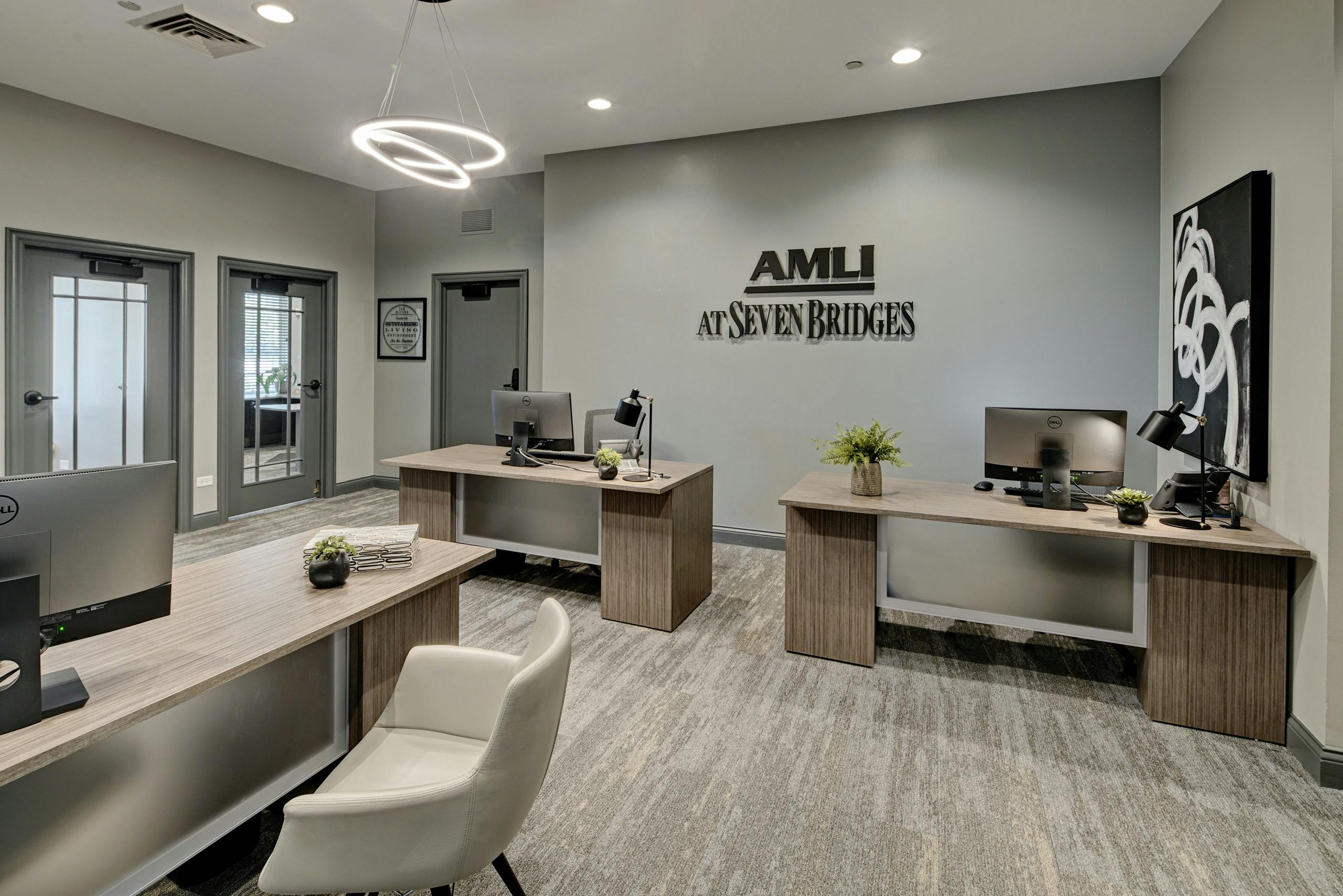 Leasing office of AMLI at Seven Bridges with 3 desks with computers and community logo on gray wall and doors to private offices