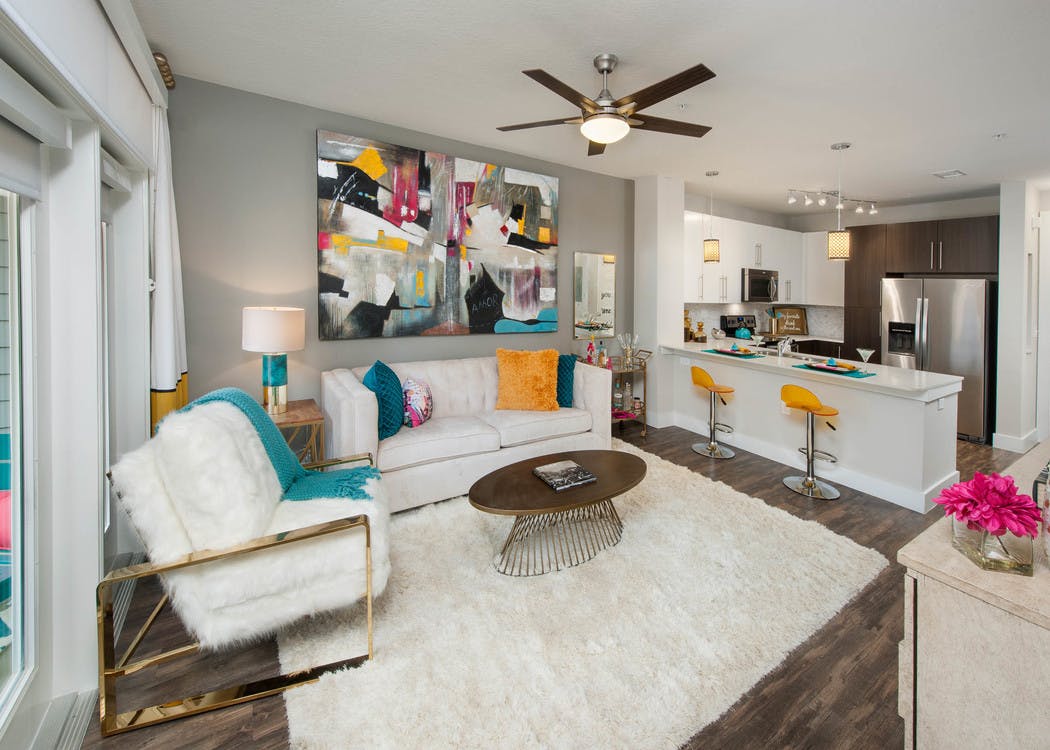 AMLI Piedmont Heights kitchen and living room showing white couches and grey walls with dark floor and counter with barstools