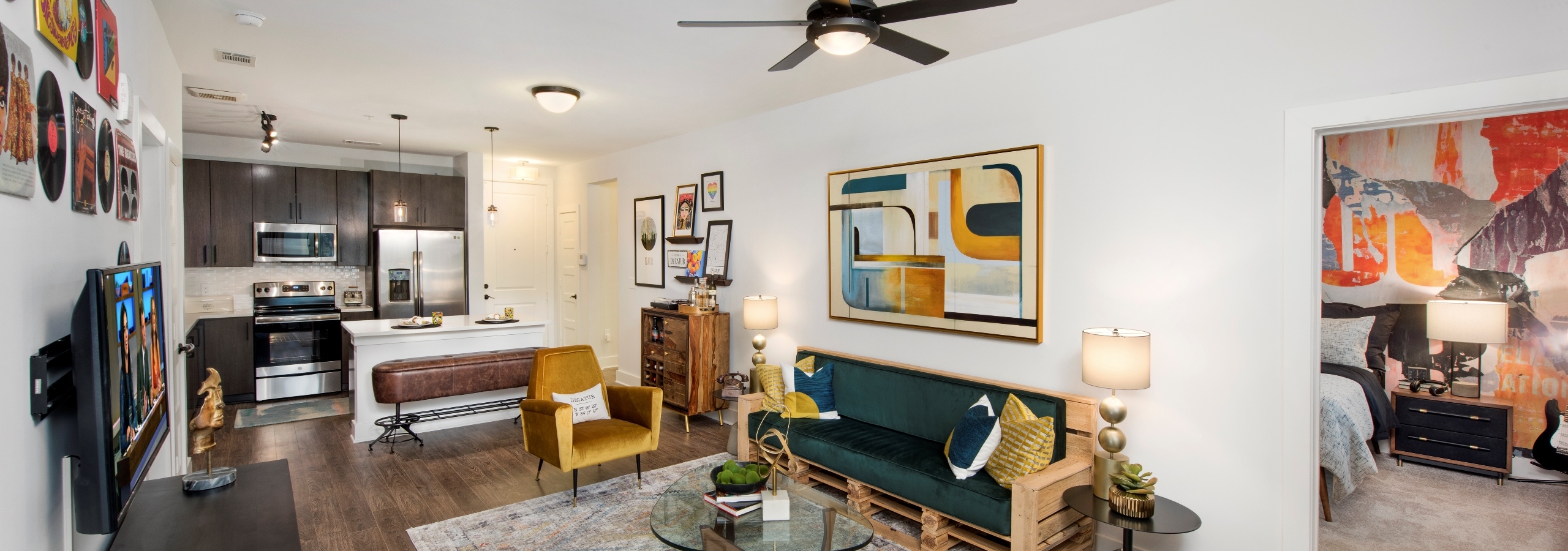 Interior of AMLI Decatur apartment kitchen and living room with ceiling fan and peek inside bedroom through open door