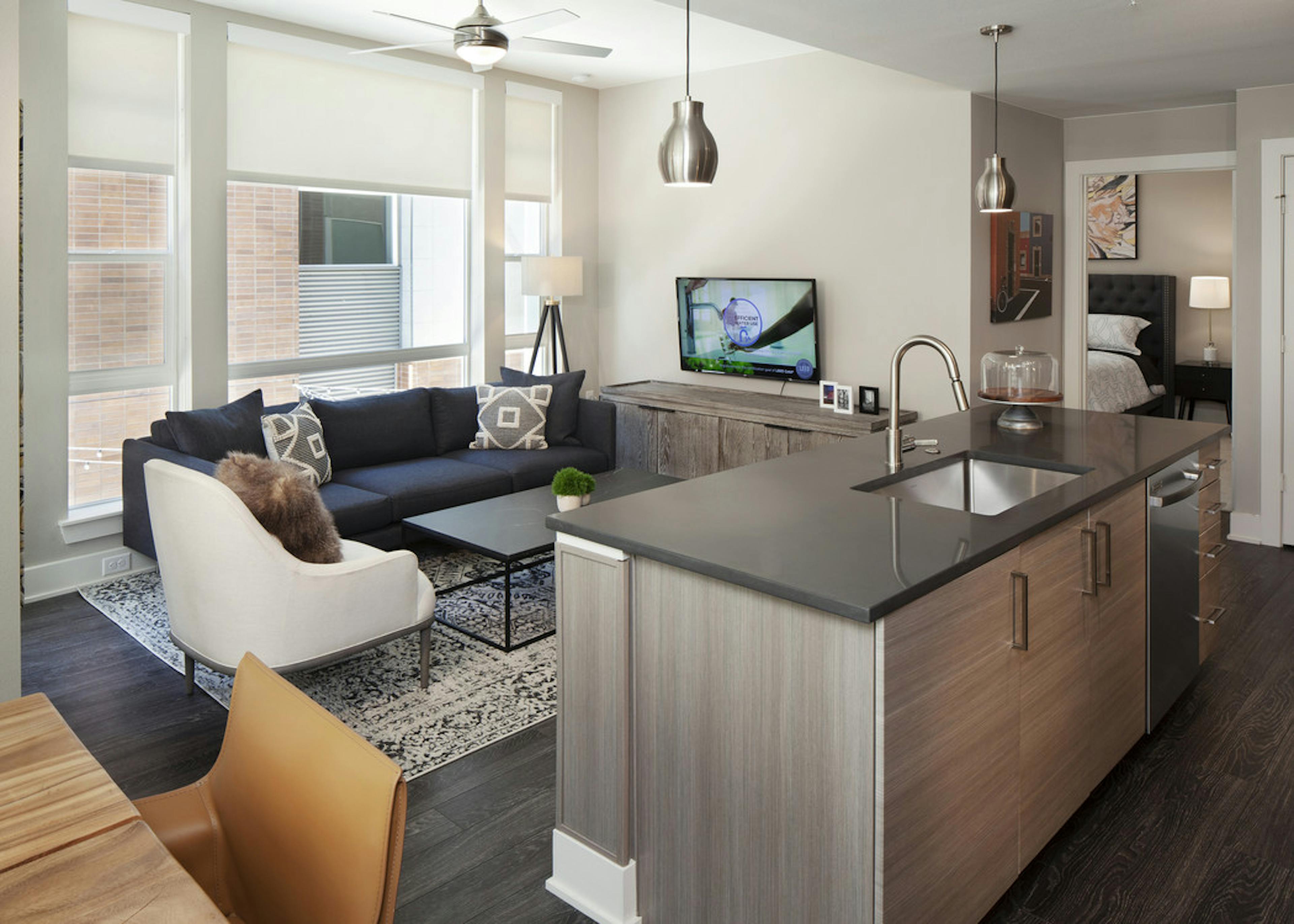 A kitchen island at AMLI Riverfront Green apartment and living room with a large window and a view into the bedroom
