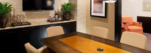 Interior view of conference room at AMLI at Escena apartment building with wood table and chairs and big screen TV