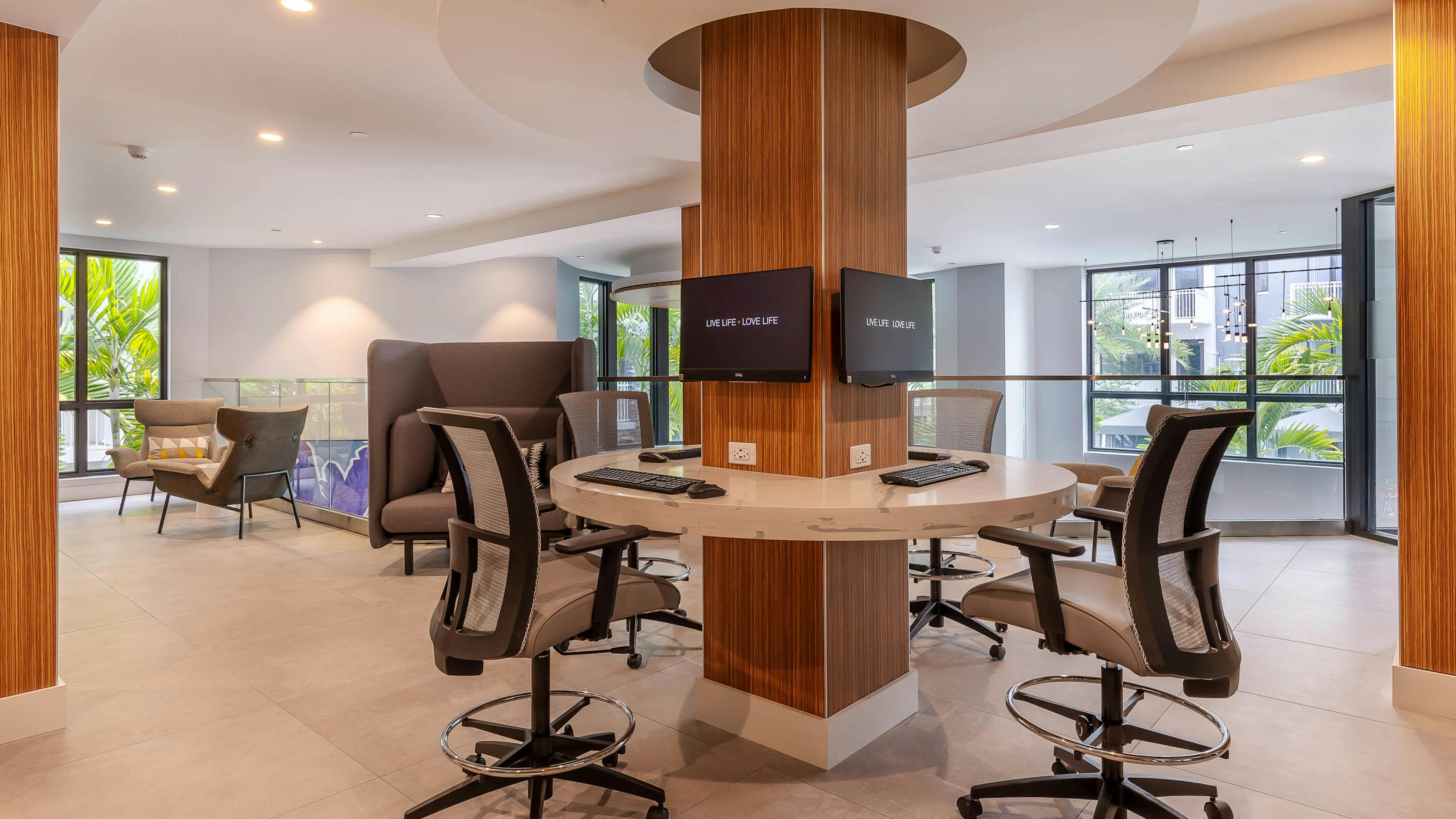 AMLI Park West apartment business center with desk chairs around a circular marble desk and mounted computers on a column 