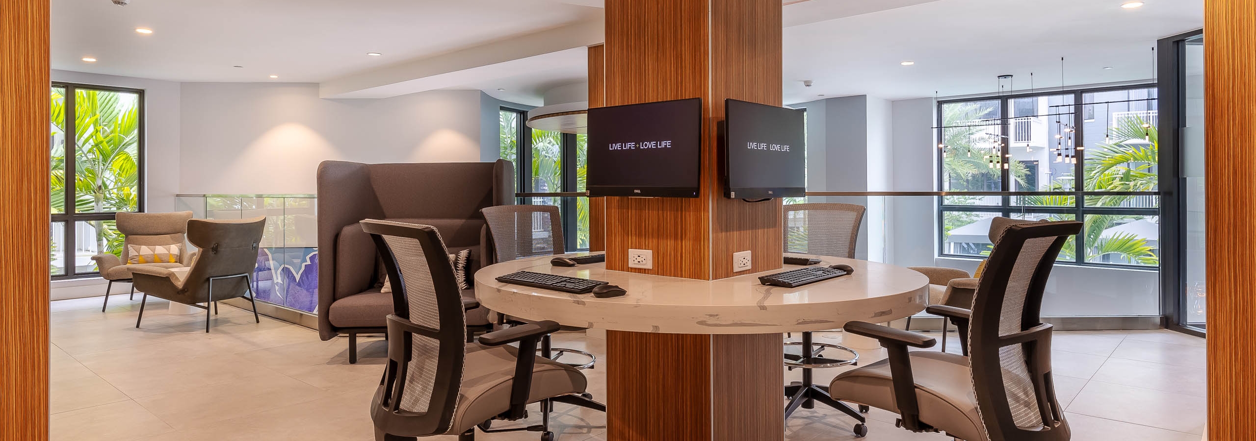 AMLI Park West apartment business center with desk chairs around a circular marble desk and mounted computers on a column