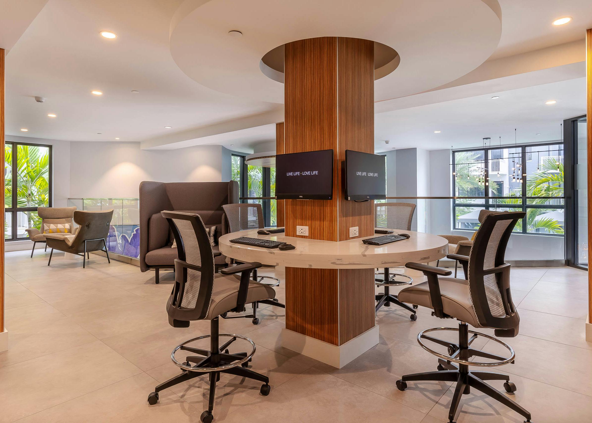 AMLI Park West apartment business center with desk chairs around a circular marble desk and mounted computers on a column