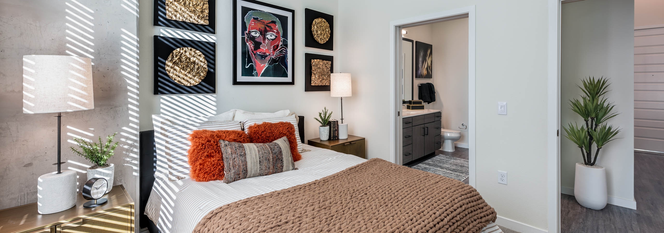 AMLI Art District bedroom with vaulted ceilings a bed with two side tables and lamps and view of the bathroom and living room