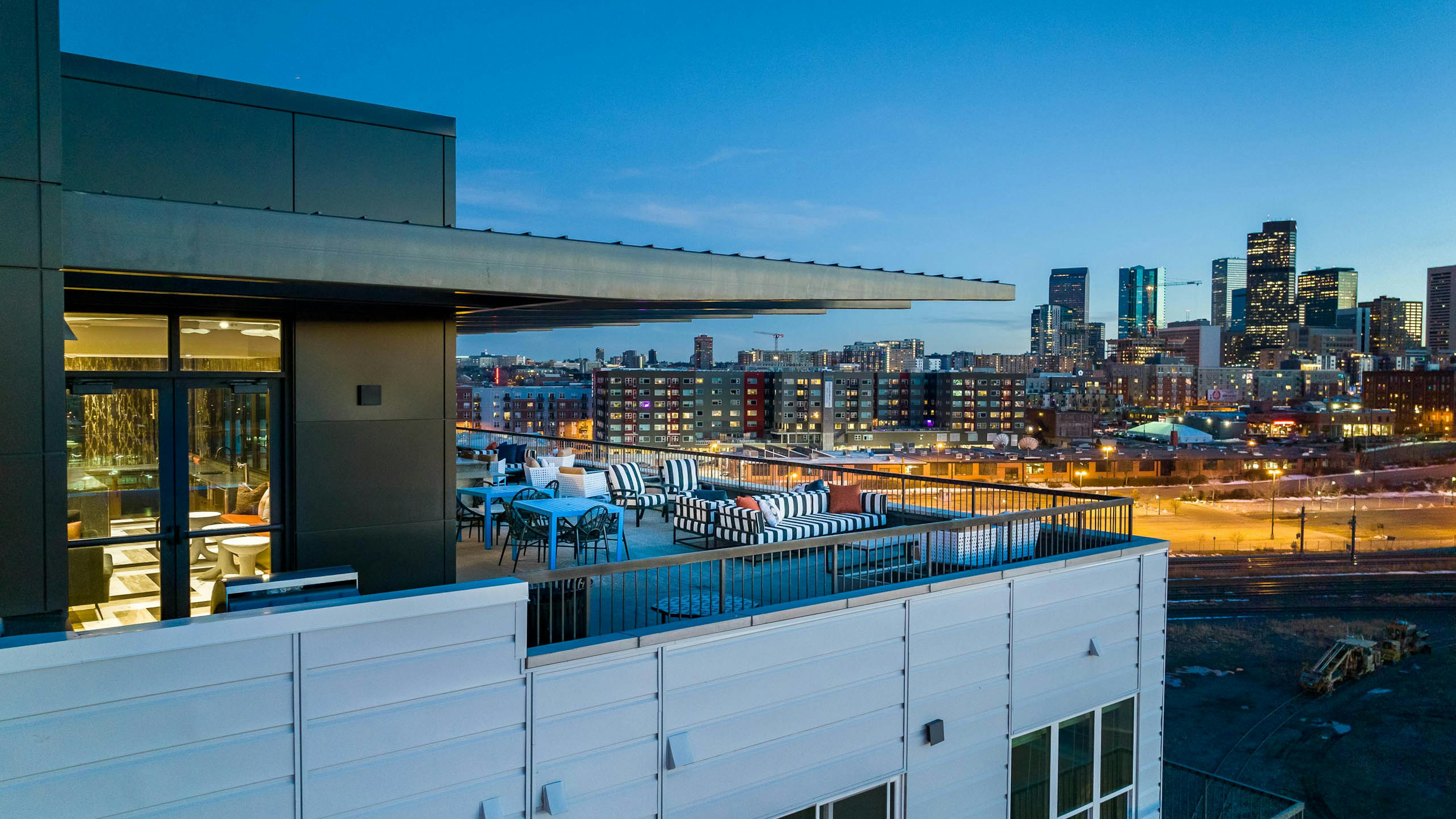 Exterior view of the sky lounge at AMLI Art District with canopy covering tables and chairs and a view of the Denver skyline
