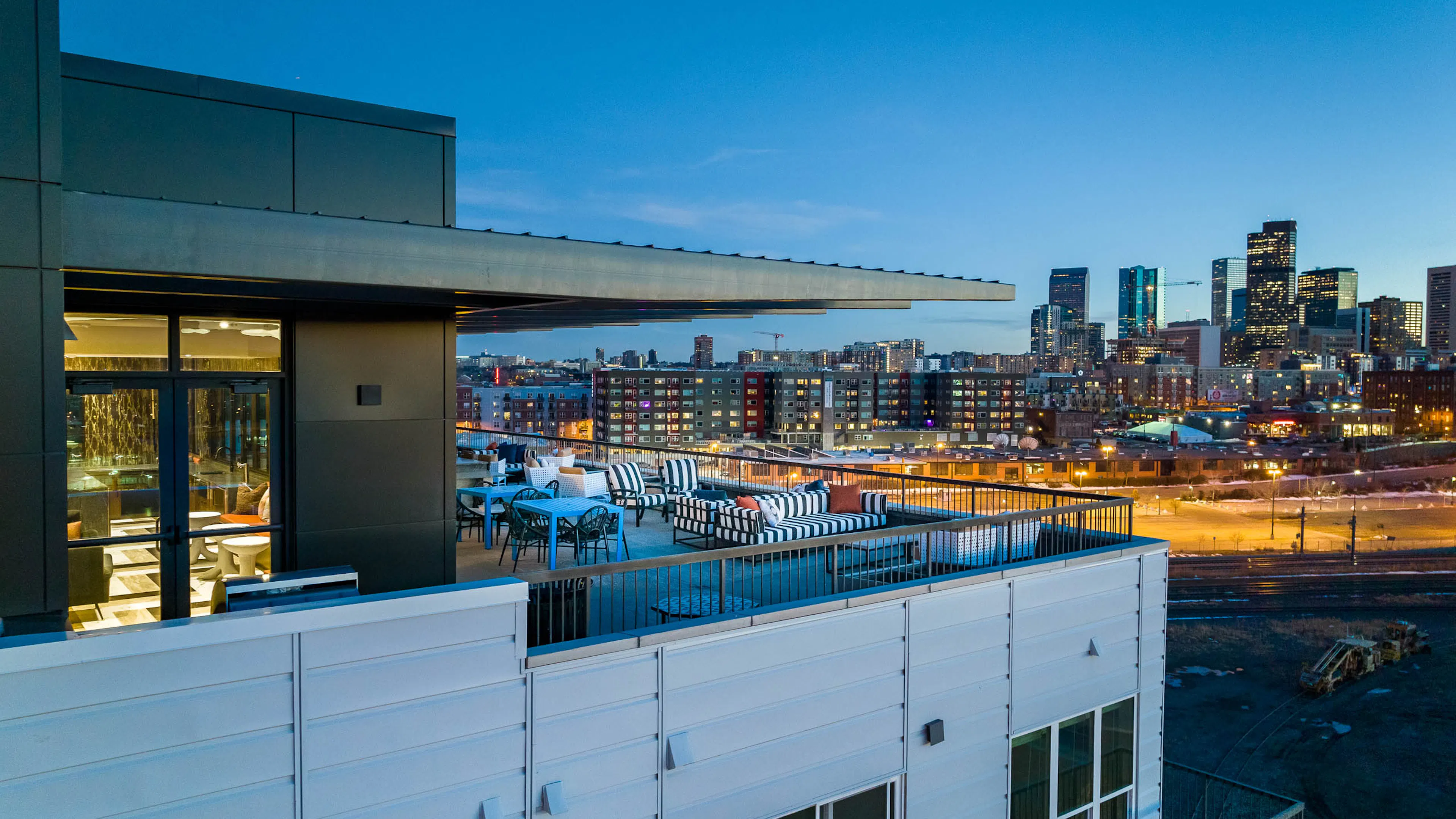 Exterior view of the sky lounge at AMLI Art District with canopy covering tables and chairs and a view of the Denver skyline