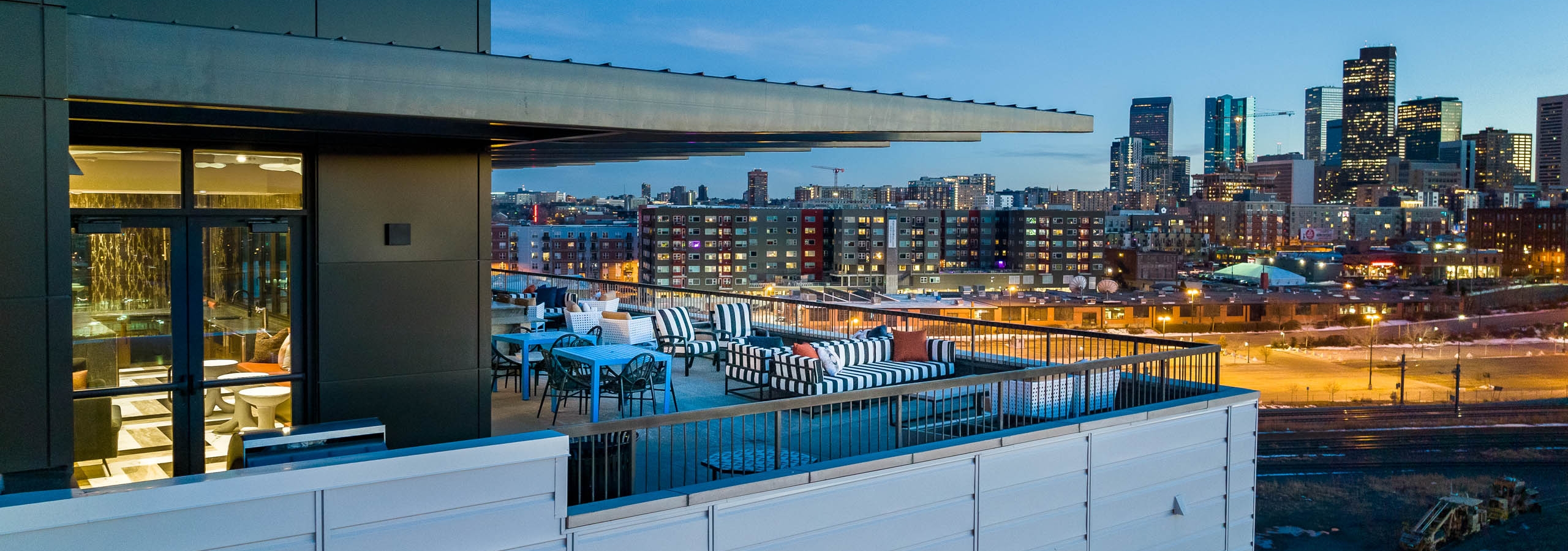 Exterior view of the sky lounge at AMLI Art District with canopy covering tables and chairs and a view of the Denver skyline