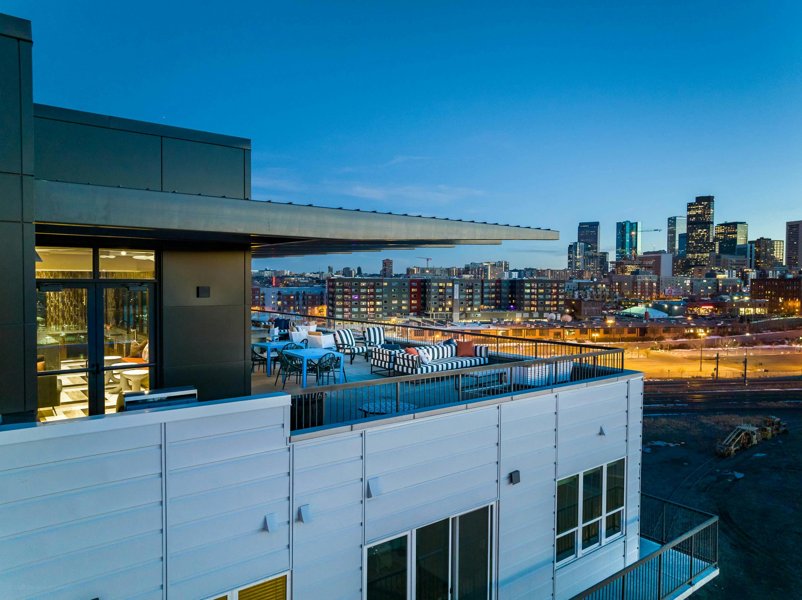 Exterior view of the sky lounge at AMLI Art District with canopy covering tables and chairs and a view of the Denver skyline
