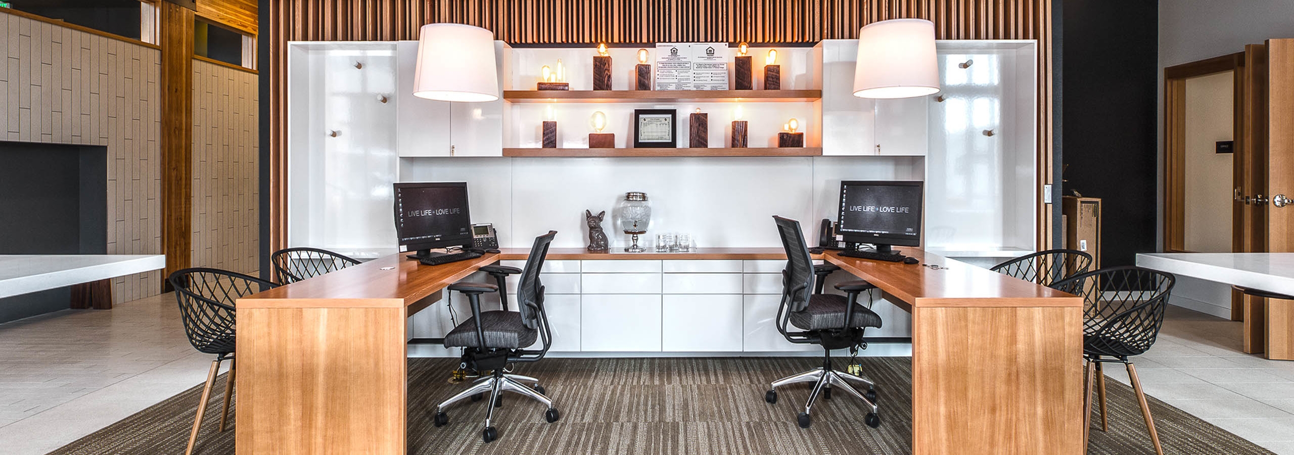 The leasing office at AMLI Wallingford with two leasing desks and chairs and white wall with unique lights