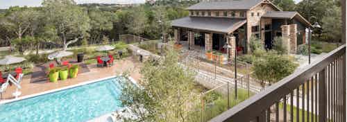 Exterior view of pool at AMLI Covered Bridge with colorful poolside dining seating and an accessibility pool lift