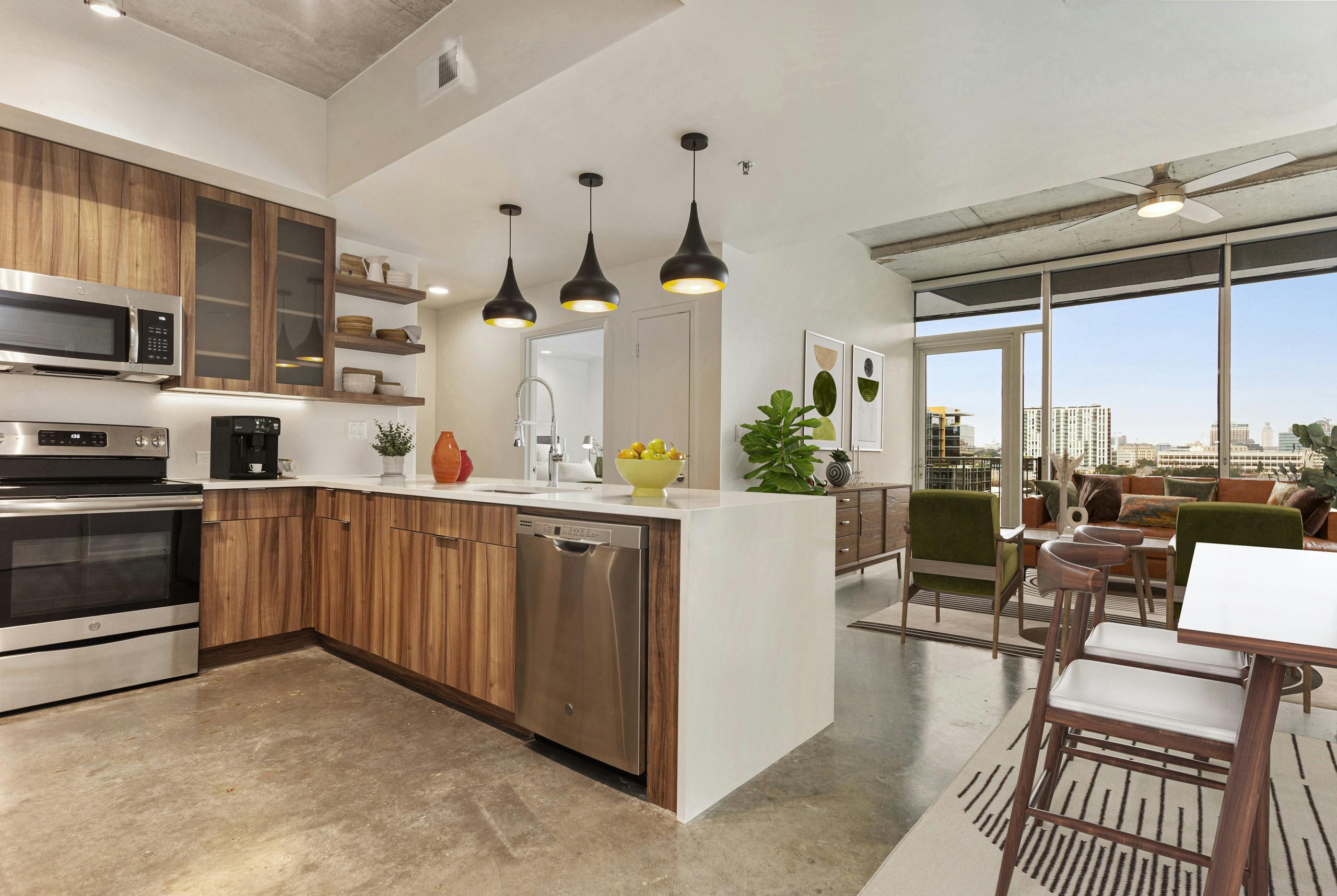 AMLI on 2ND kitchen with wood grain cabinets and 3 pendant lights adjacent to living room with floor to ceiling windows