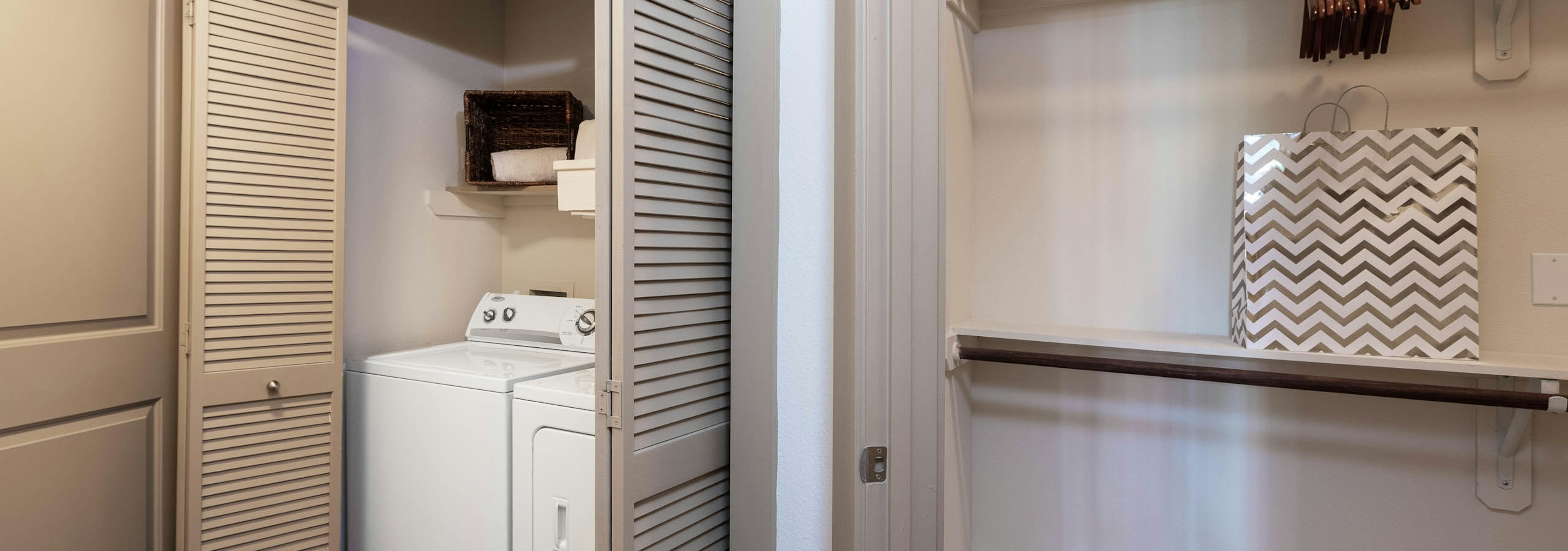 Interior view of two white laundry machines tucked in a closet with folding doors at AMLI Eastside apartment community