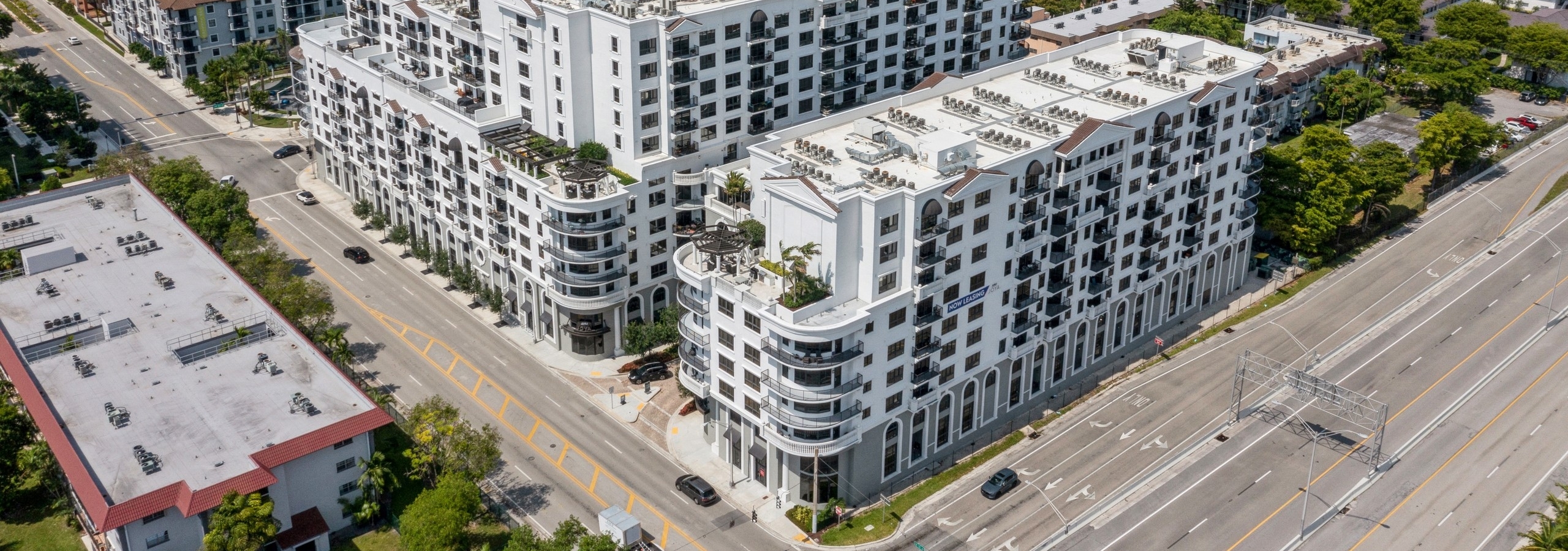 Close up aerial view of AMLI Joya apartment buildings surrounded by buildings and trees and blue sky in the distance
