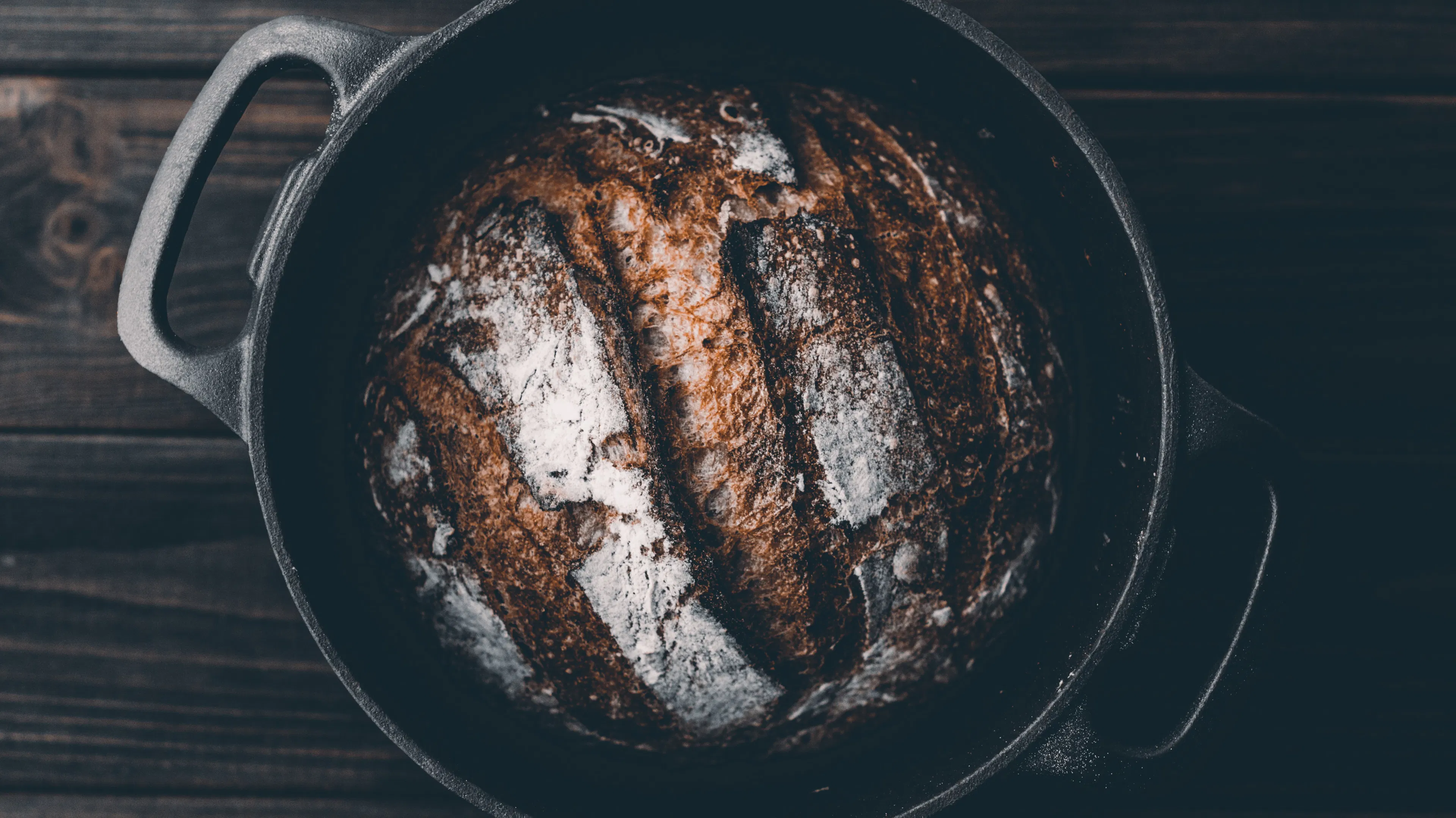 A Dutch oven photographed from above with a loaf of fresh bread inside