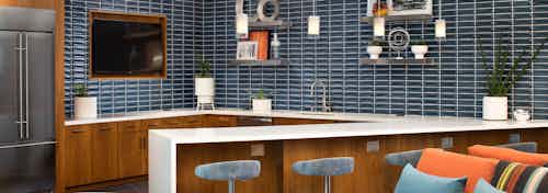 Interior of clubhouse catering kitchen at AMLI Uptown Orange apartments with big screen TV, blue tile backsplash and fridge