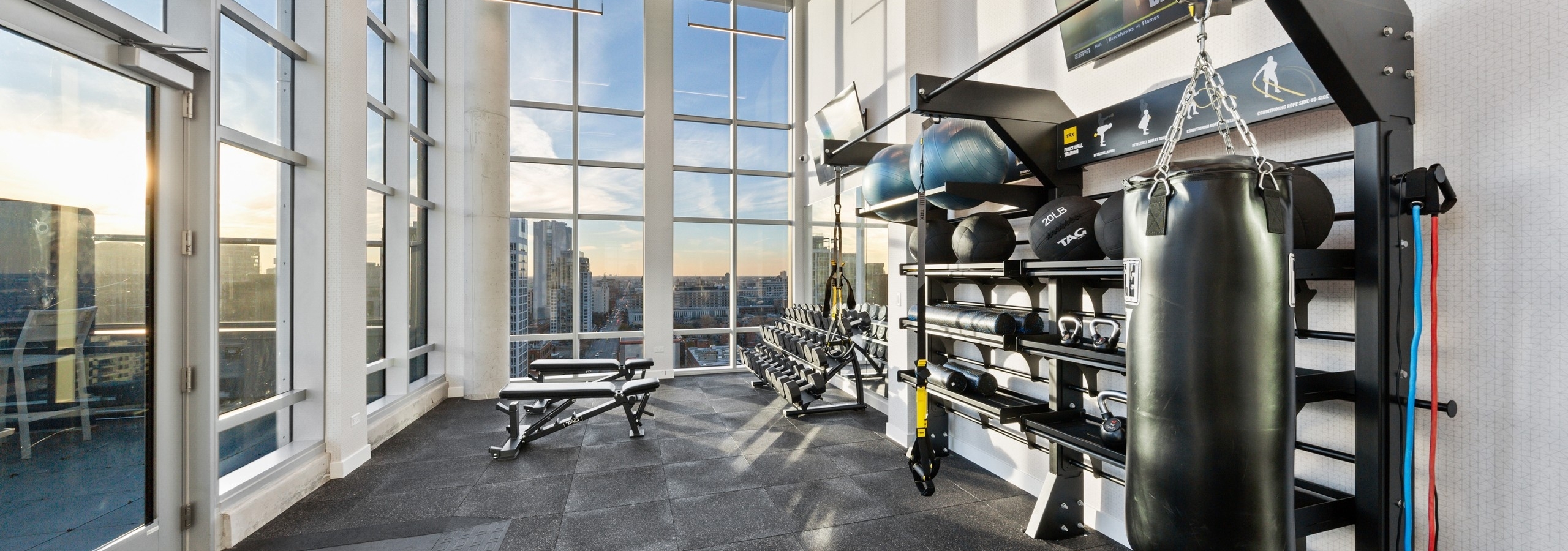 AMLI 808 fitness center with floor to ceiling windows featuring a dumbell rack as well as medicine balls and a boxing bag