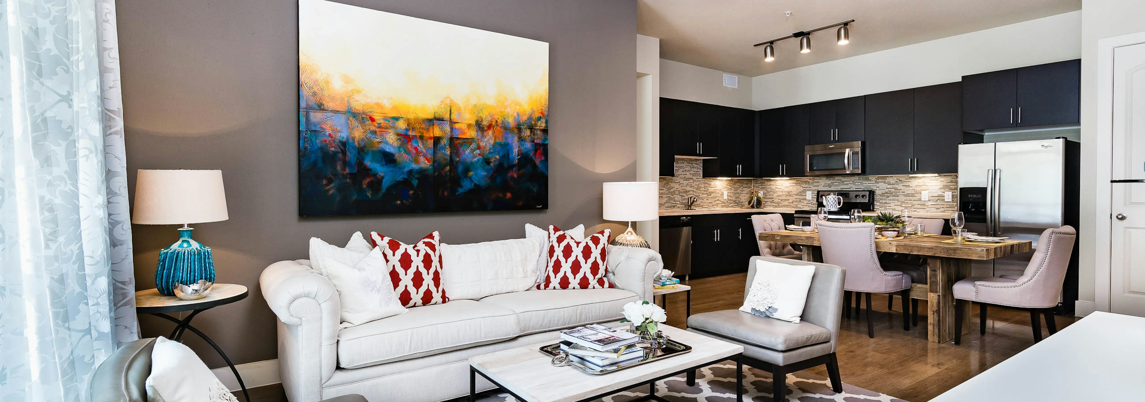 Interior of AMLI RidgeGate furnished living room with white sofa facing dining area and kitchen with mosaic tile backsplash