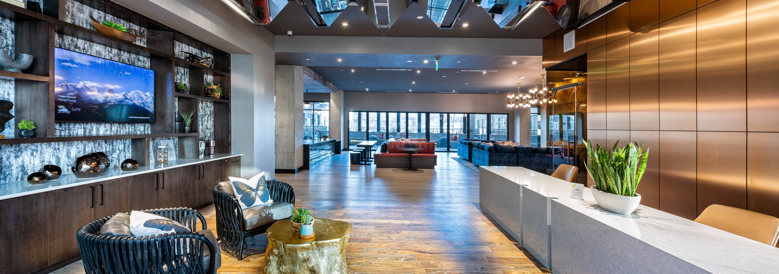 Interior view of the AMLI Art District leasing office with a desk and chairs with an ottoman and a view of resident lounge
