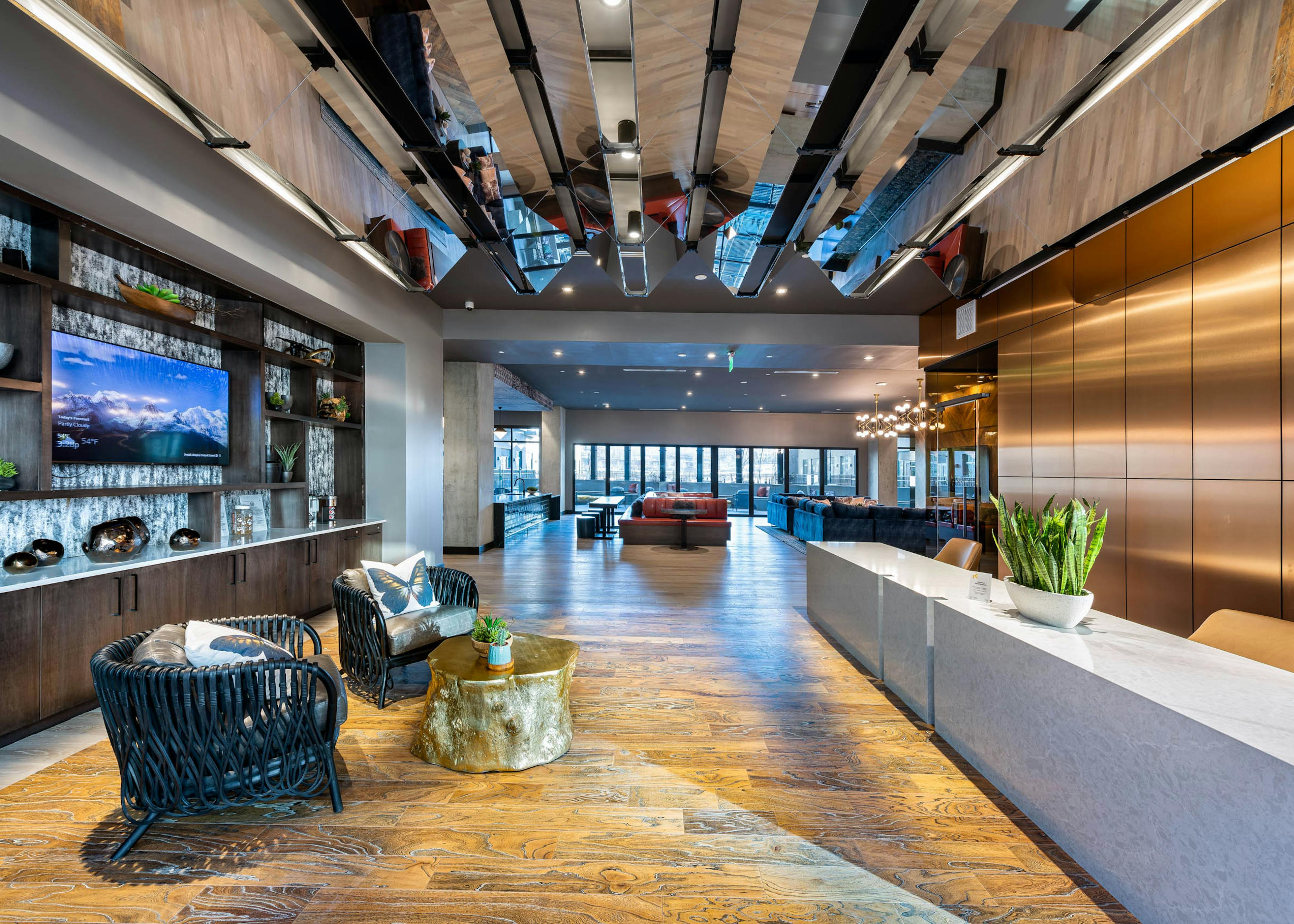 Interior view of the AMLI Art District leasing office with a desk and chairs with an ottoman and a view of resident lounge