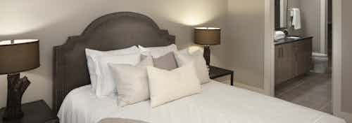 Interior view of a bedroom at AMLI Riverfront green apartments with stylish lamps as well as a peek into the bathroom